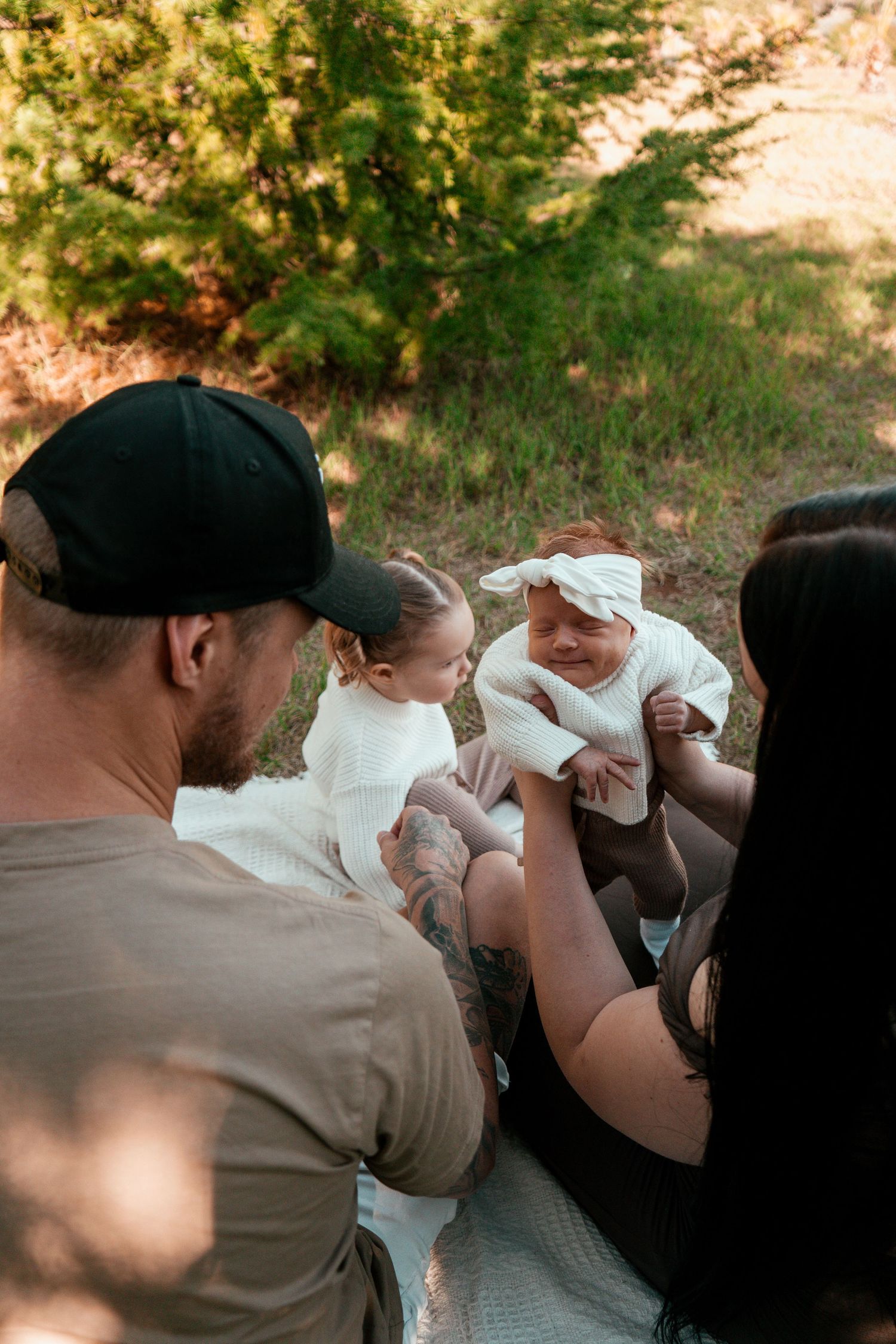A candid family moment captured during an outdoor photo session on a white blanket.