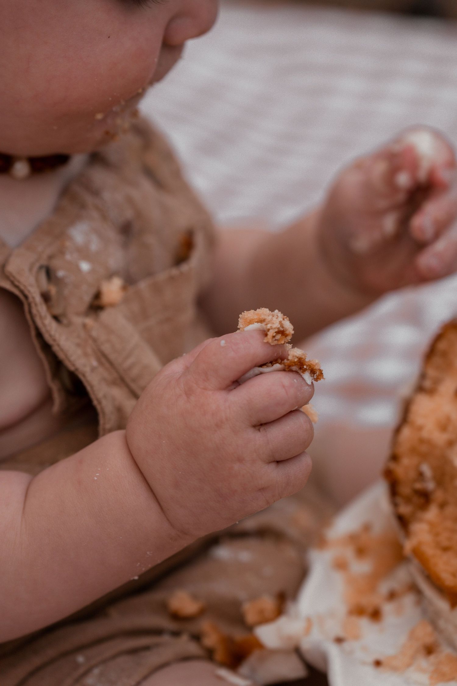 Small hands reaching for and touching bread or baked goods on a light-colored surface.