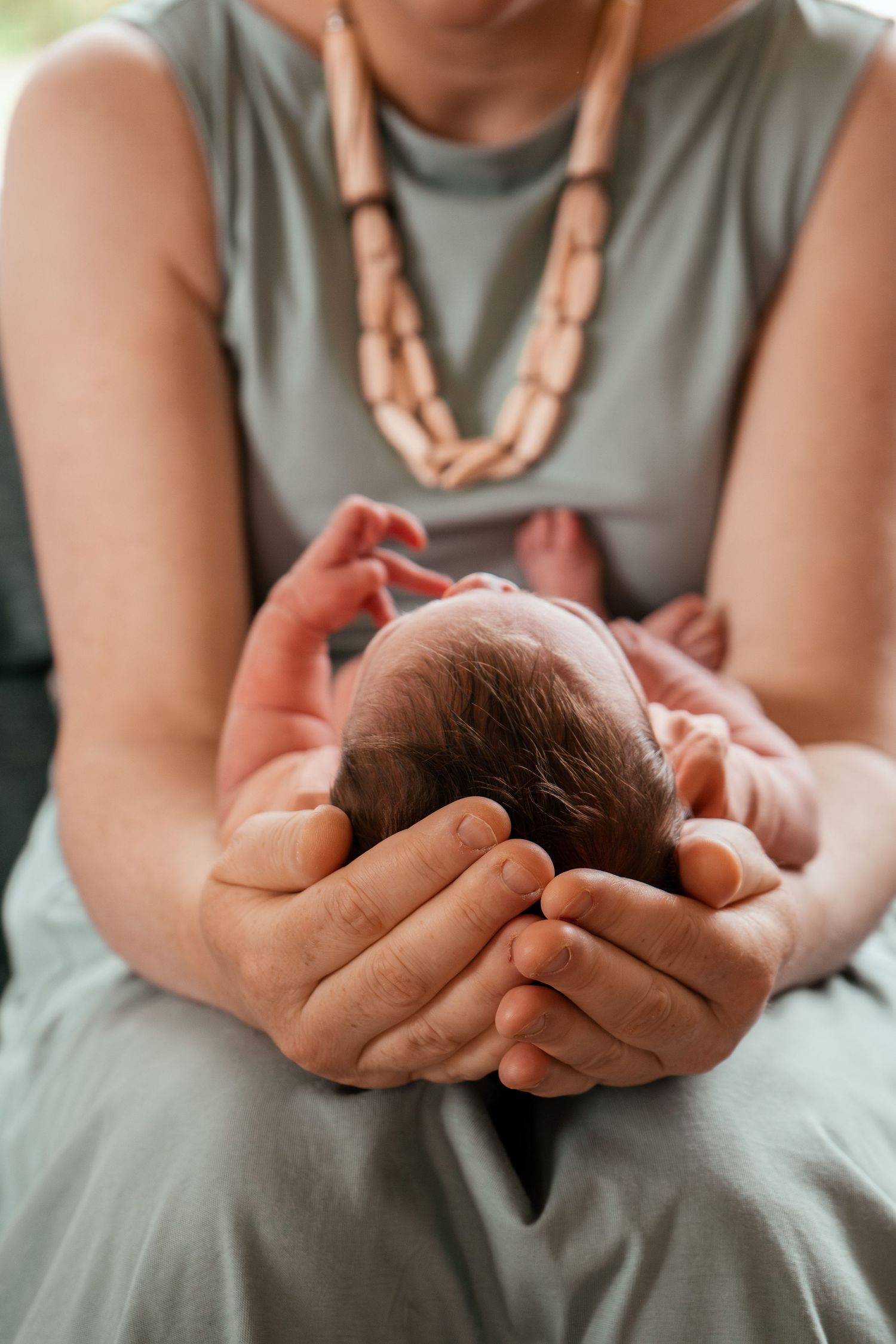 A series of photos showing hands gently cradling a sleeping newborn baby in soft lighting.