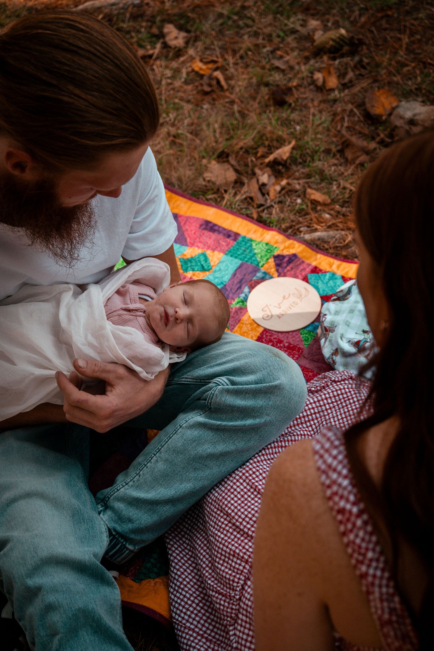 Family moment captured on colorful quilt during outdoor gathering.