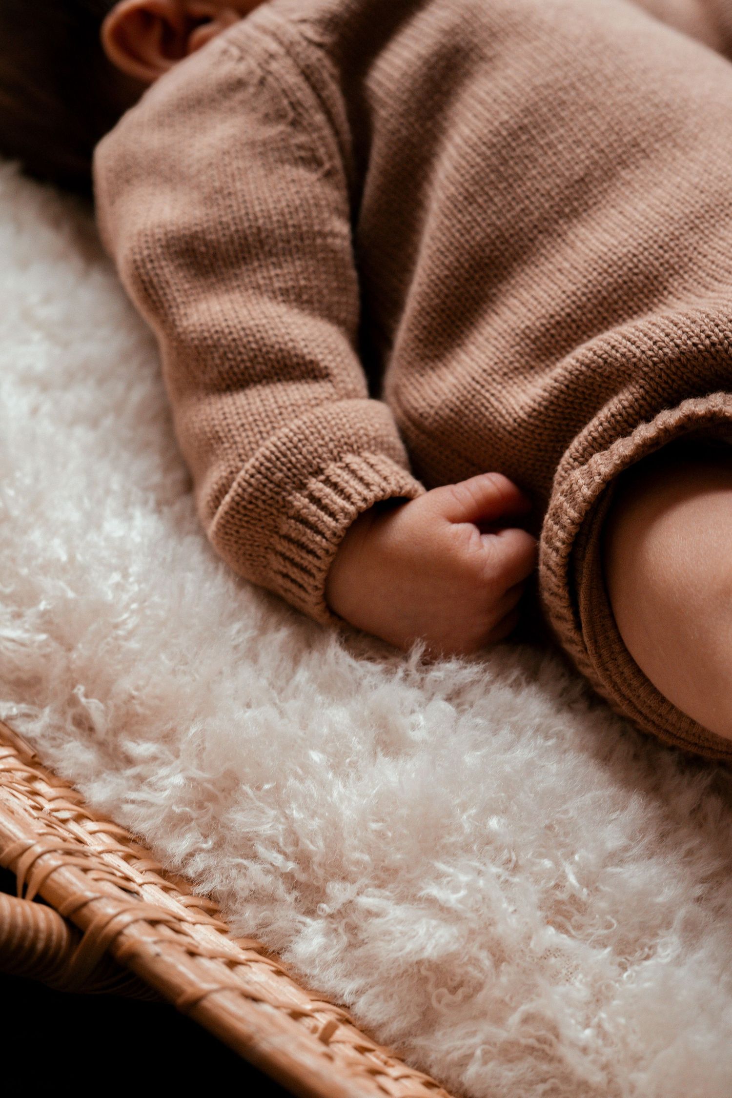 Soft brown knitted sweater fabric detail against white textured background.