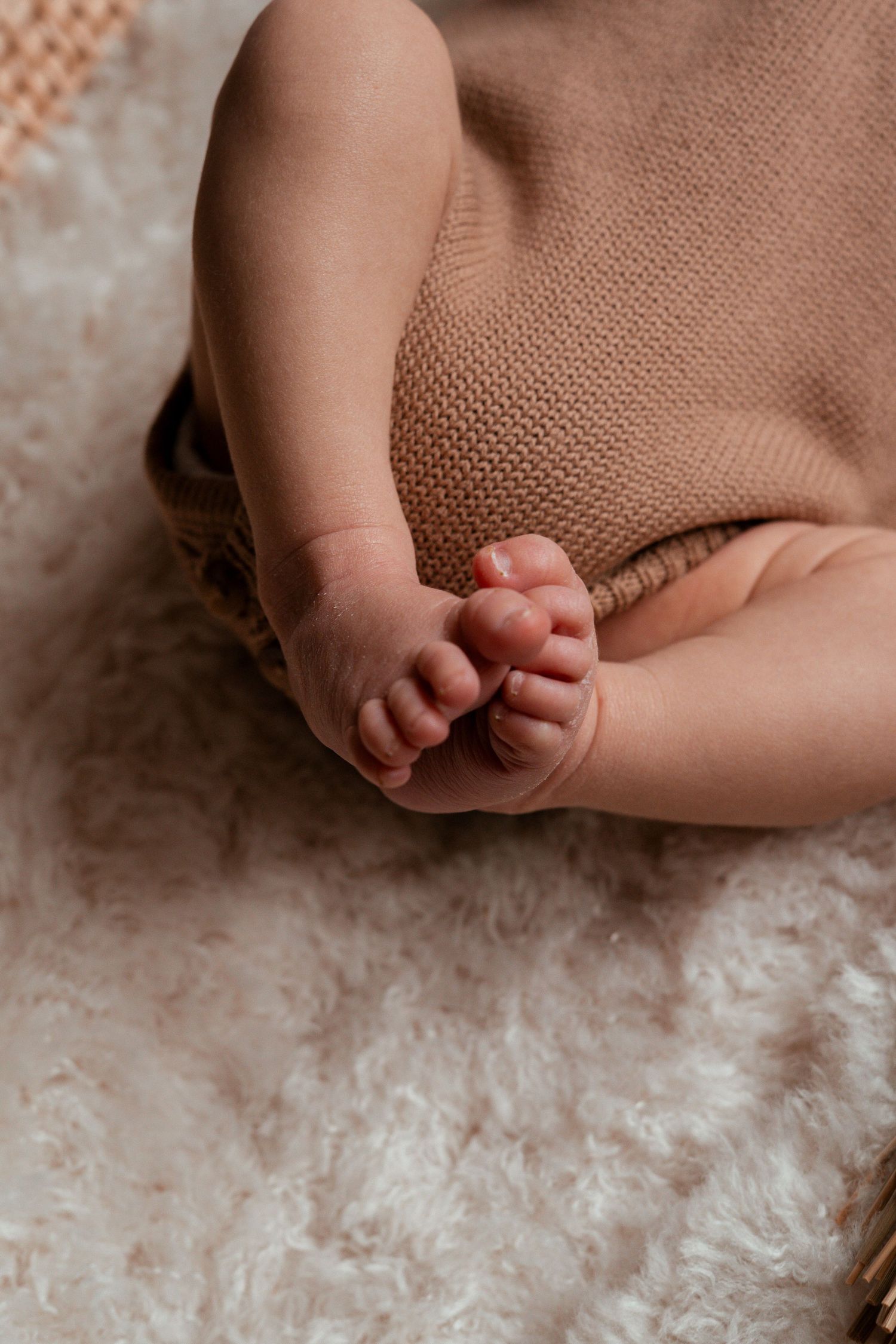 Close-up view of tiny baby feet resting on soft white textured fabric.
