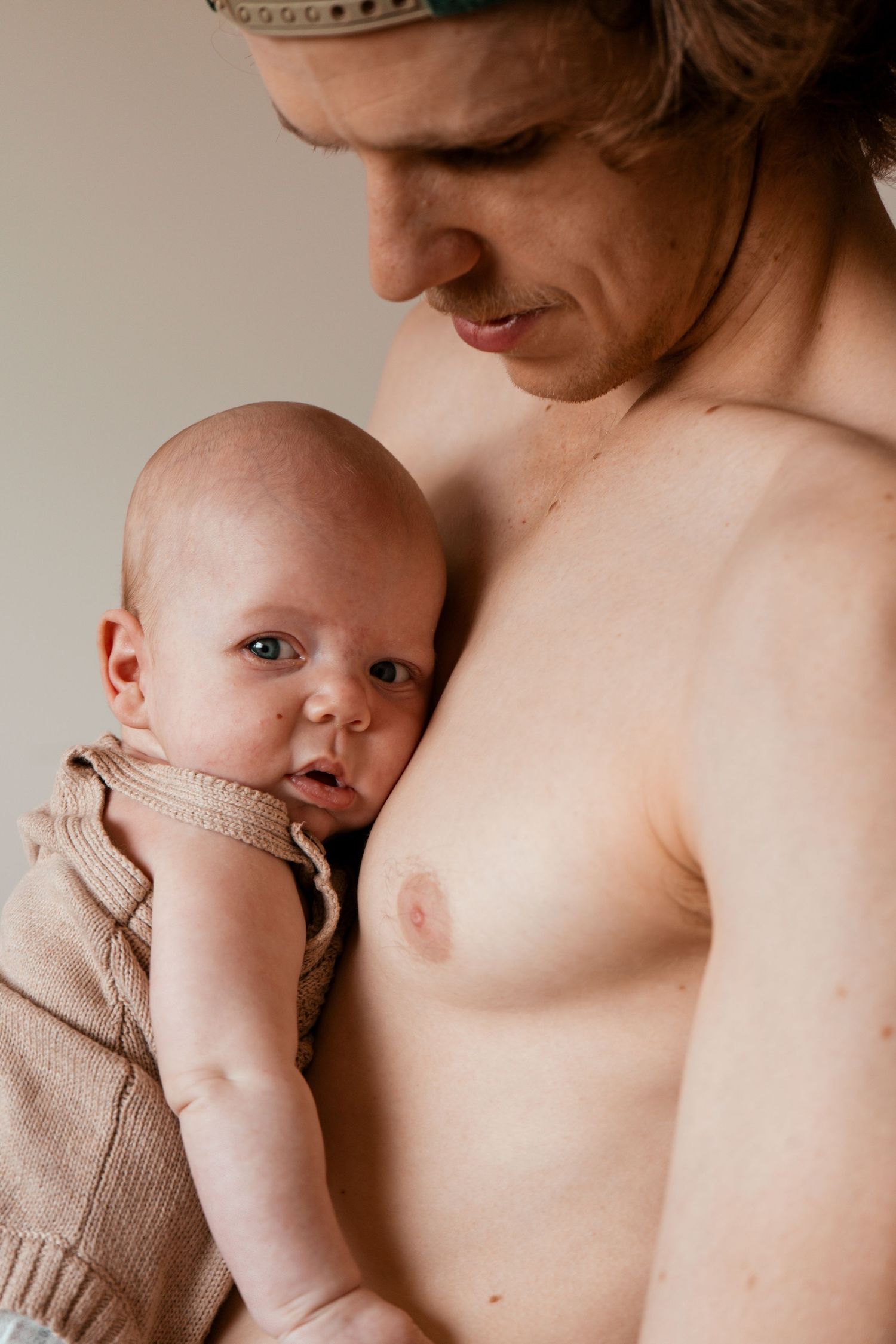 A tender moment between parent and infant in soft natural lighting.