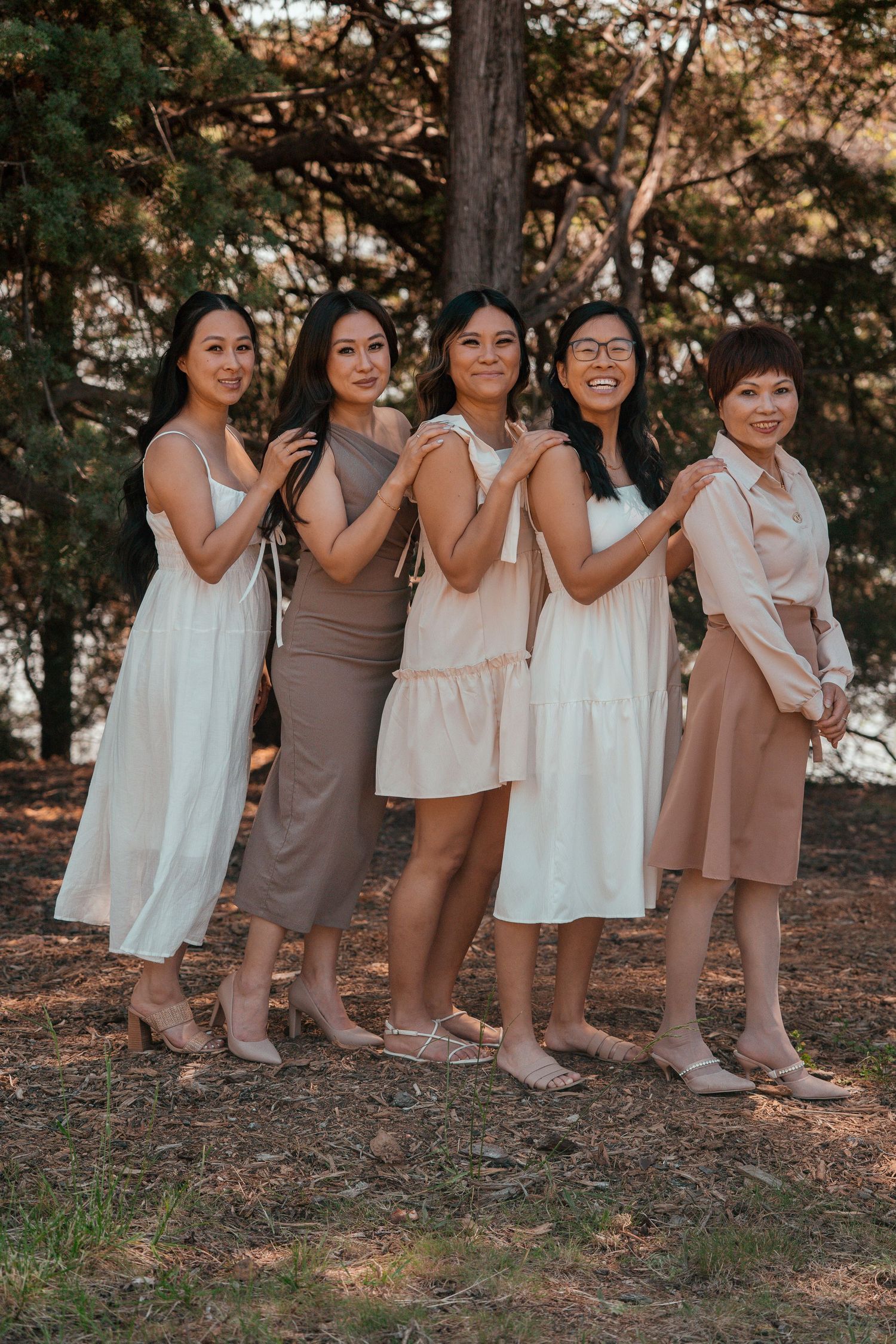 Group of children in coordinated white and brown outfits posing together on a forest floor.