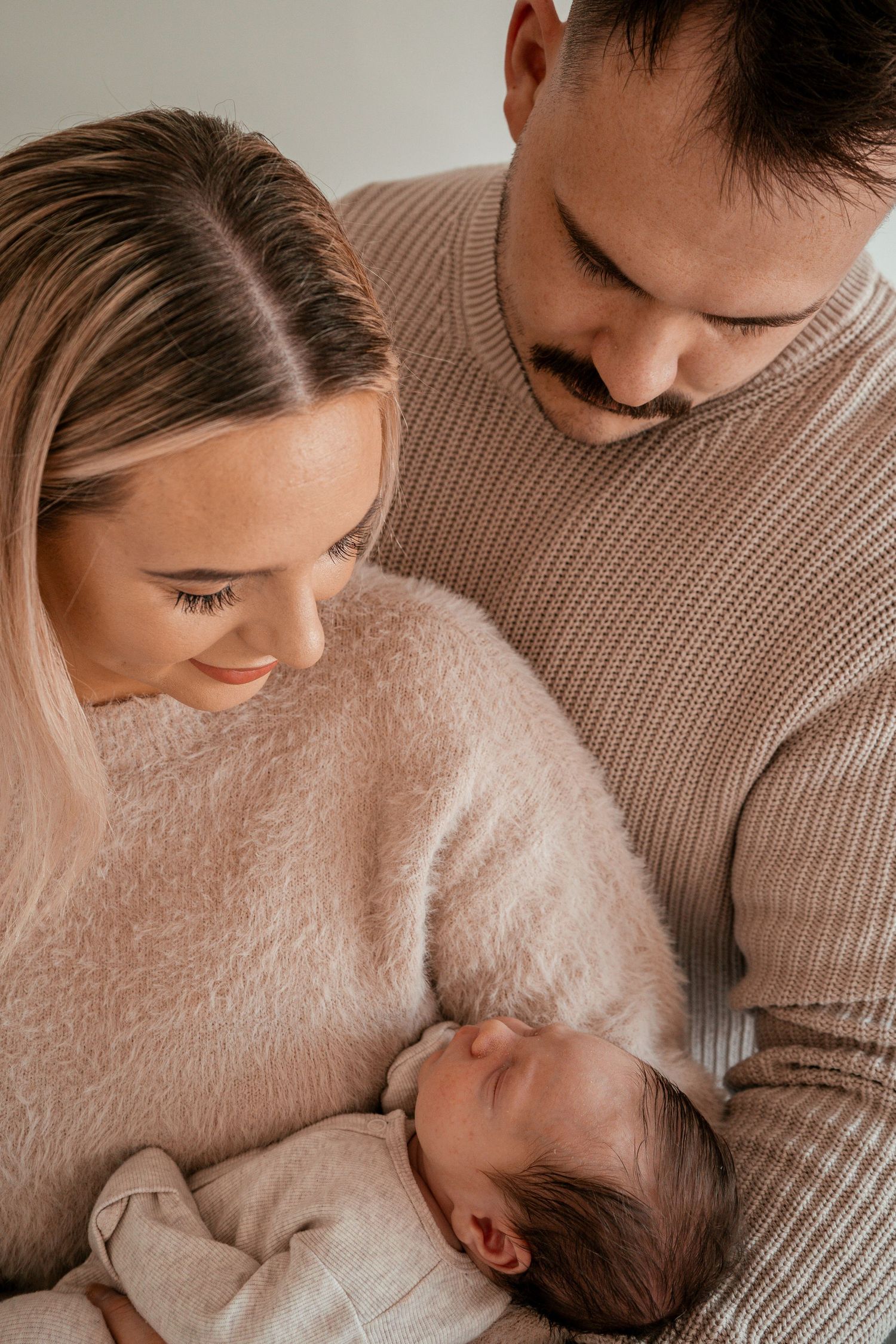 A tender moment captured in a series of intimate photos showing a parent and baby in soft beige tones.
