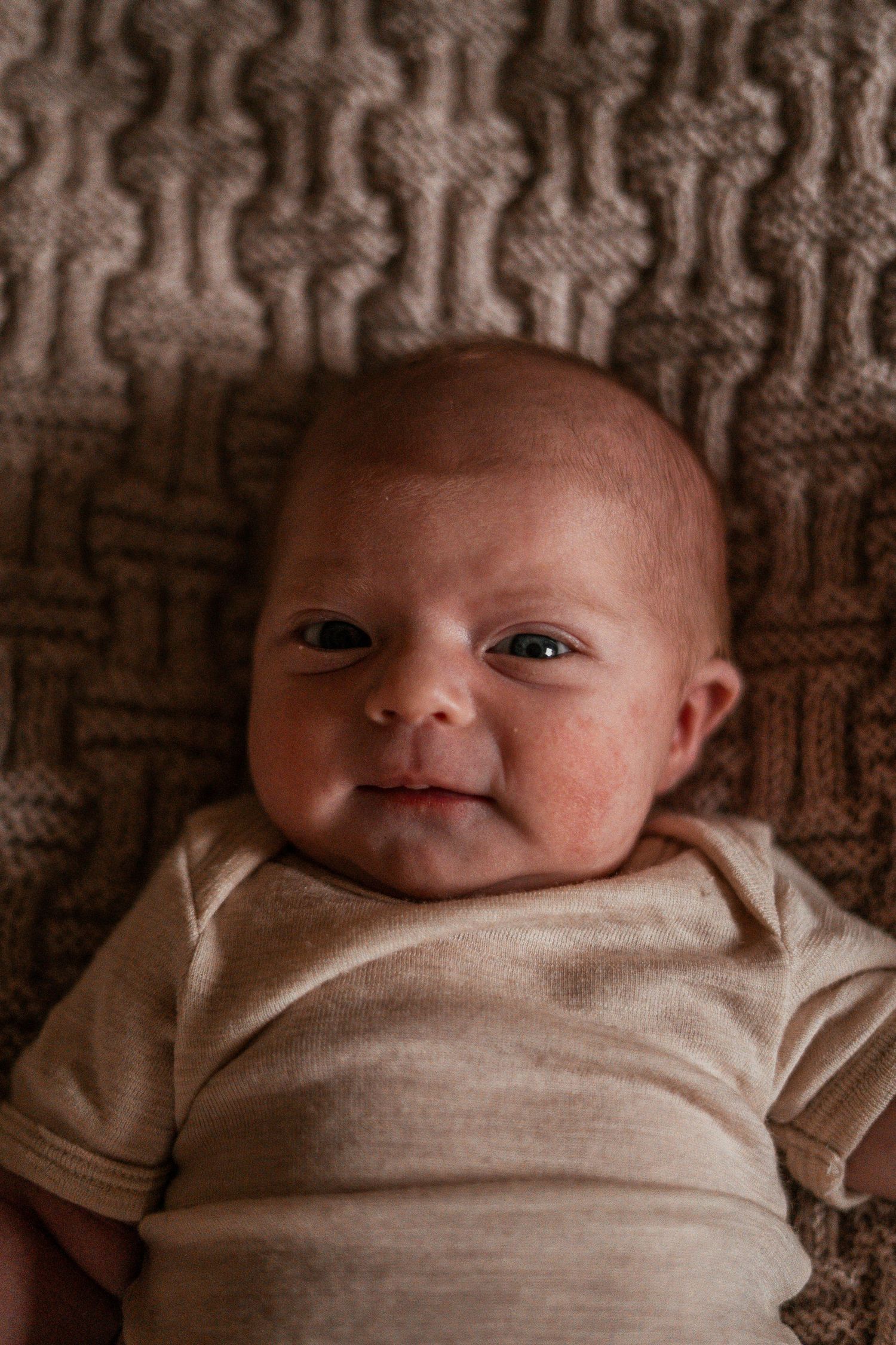 A newborn baby swaddled in white cloth shown in a series of close-up portraits.