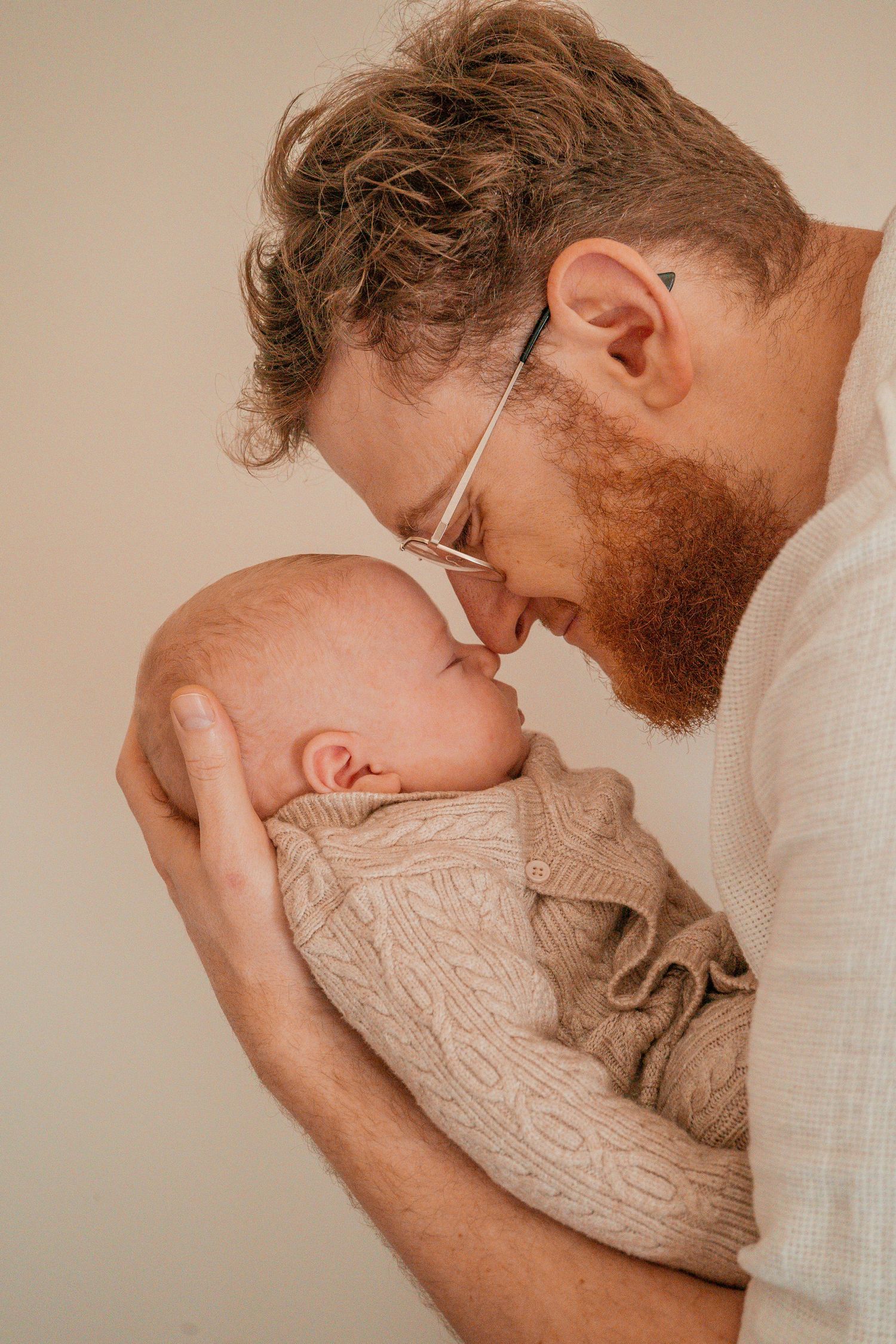 A series of intimate photos showing tender moments between a parent and newborn baby in warm, neutral tones.