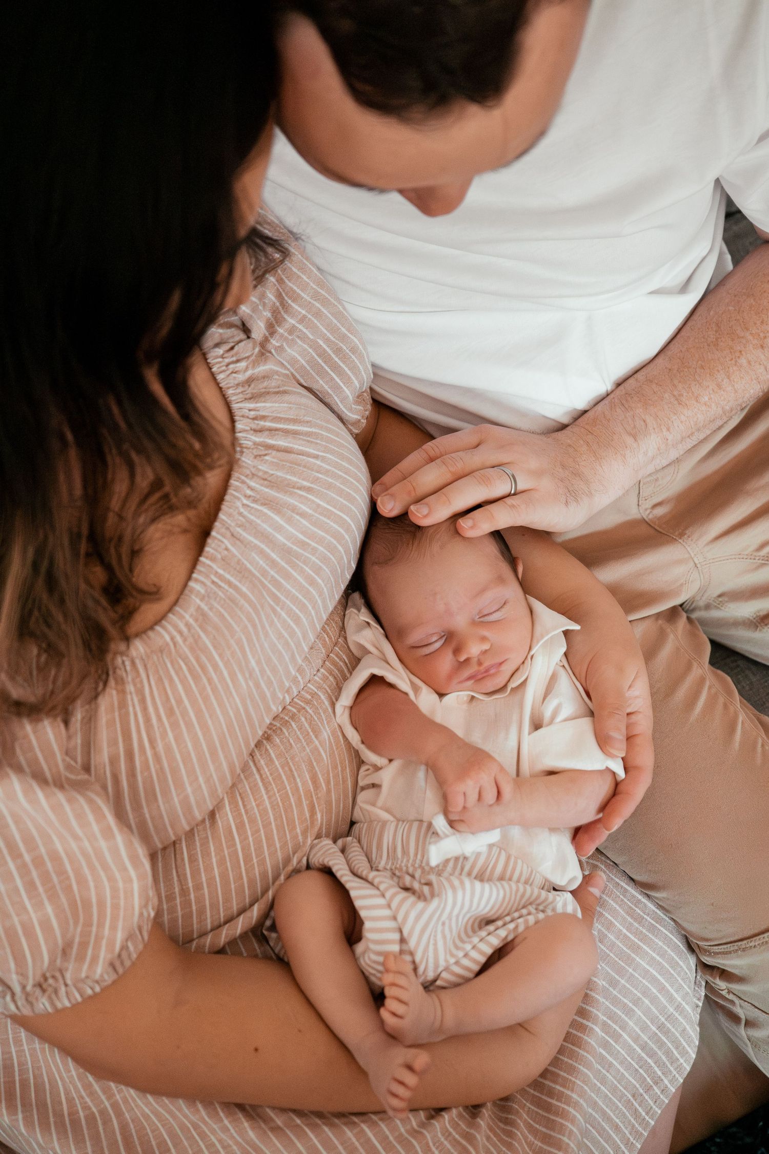 Close-up series of tender moments between parent and newborn baby in soft pink and white tones.