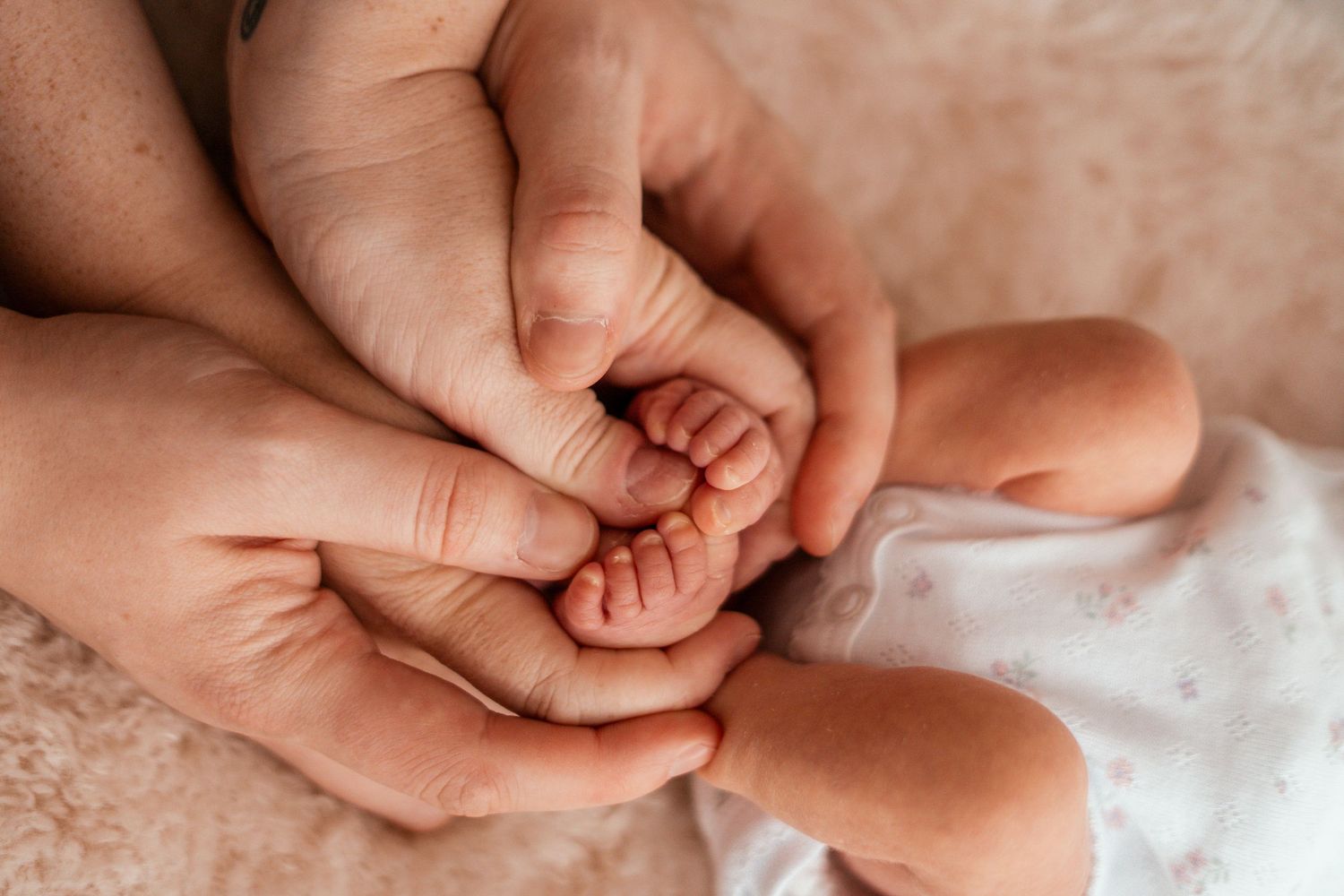 A series of tender close-up shots showing hands gently holding a newborn baby's tiny fingers and feet.