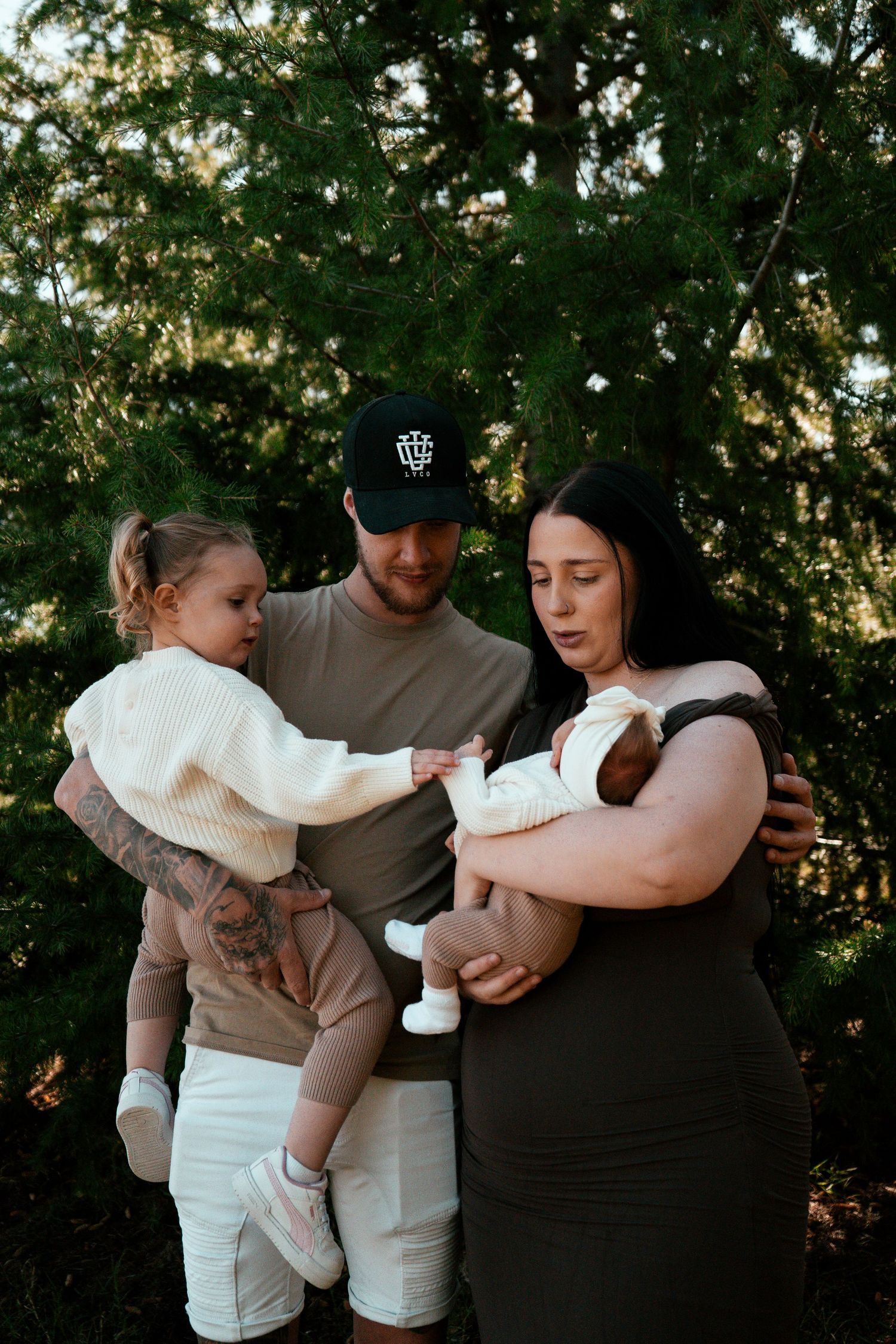 Family photo with toddler and newborn outdoors in natural lighting.