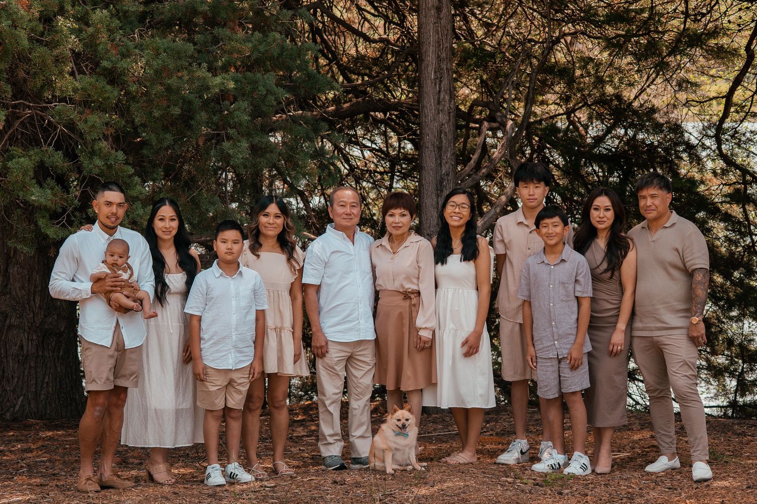 A group of people wearing coordinated neutral tones and white outfits pose together for outdoor family photos.