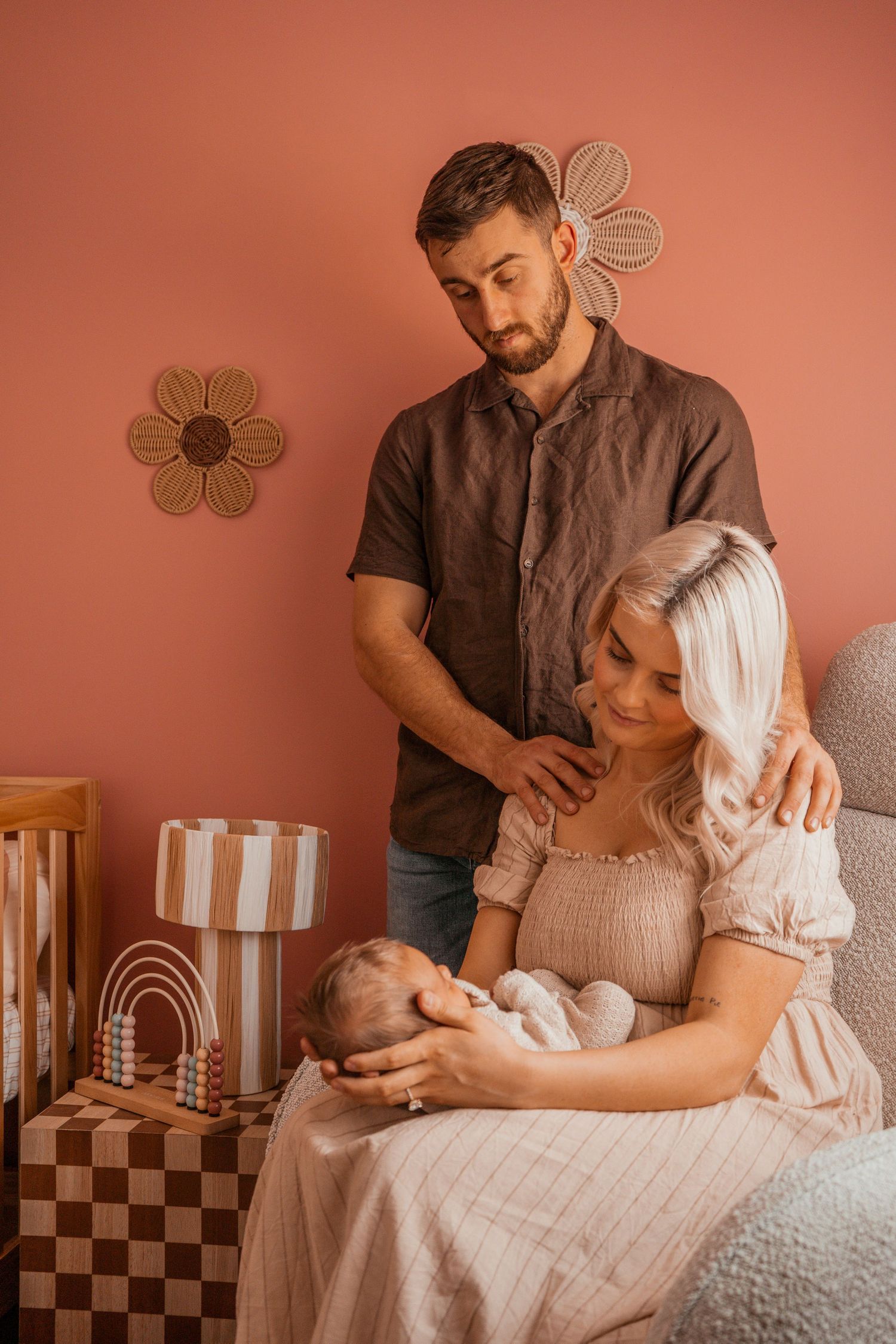 Intimate couple in vintage-style setting share tender moments against coral-colored wall with decorative flower accents.