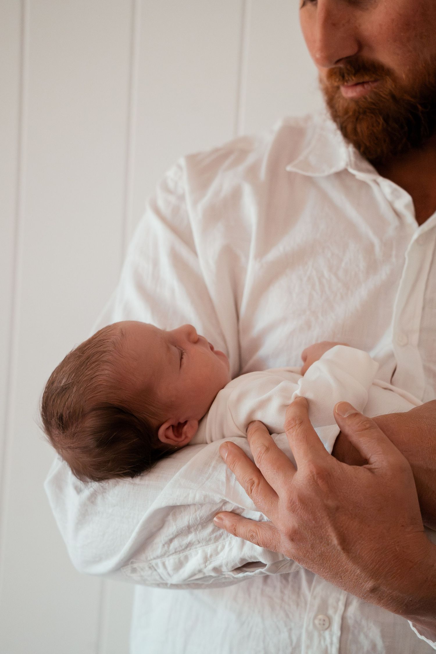 A series of tender moments showing a baby being cradled in someone's arms wearing a white shirt.