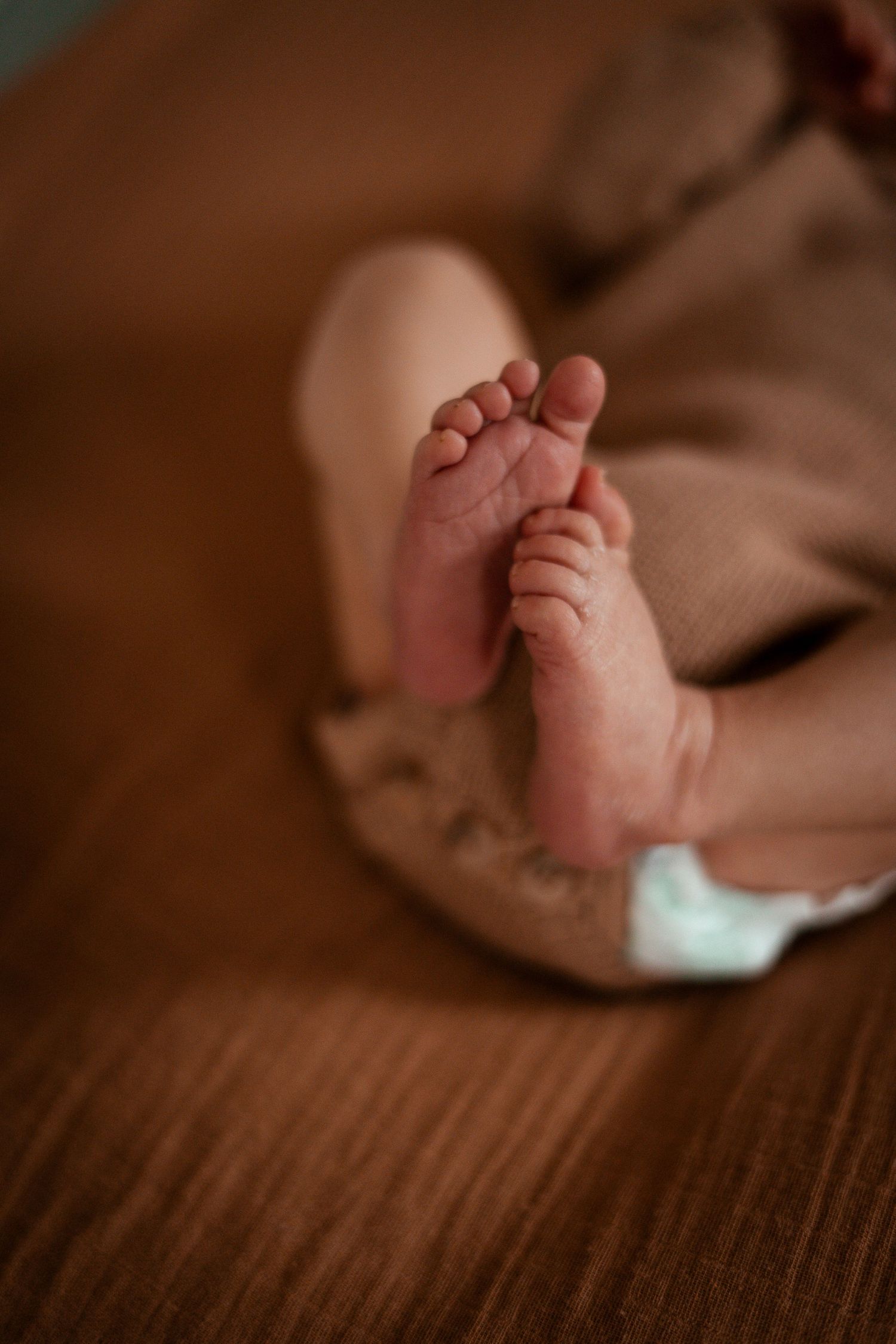 Close-up series of tiny newborn baby feet against a dark wooden surface in warm lighting.