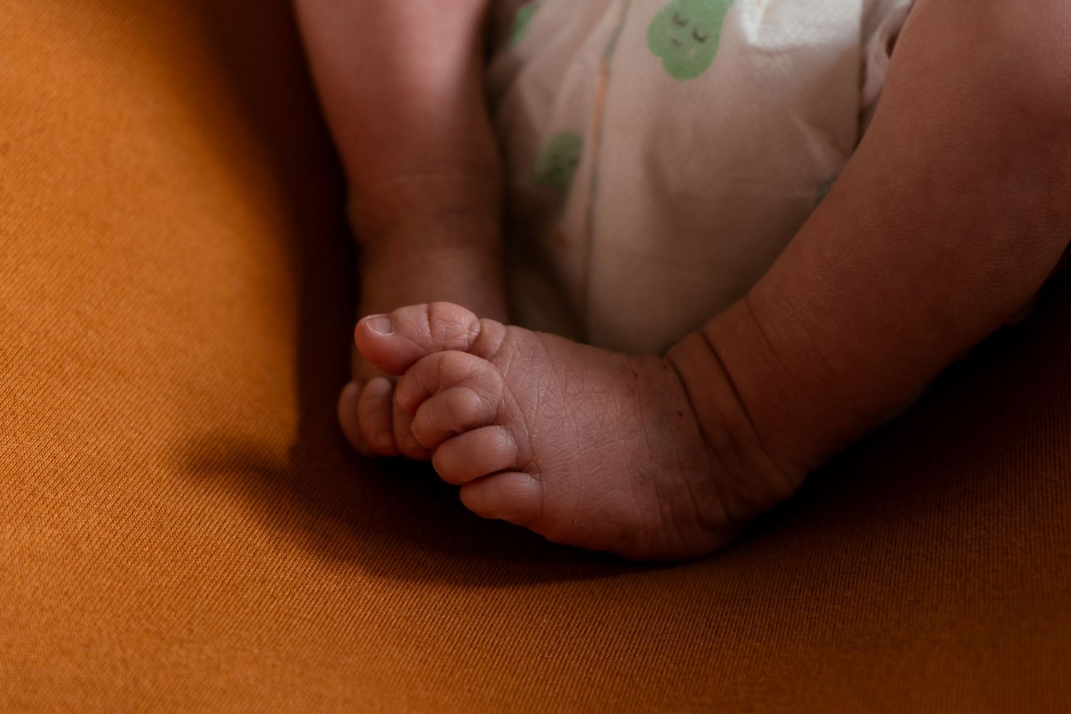 Close-up shot of tiny baby feet against orange background.