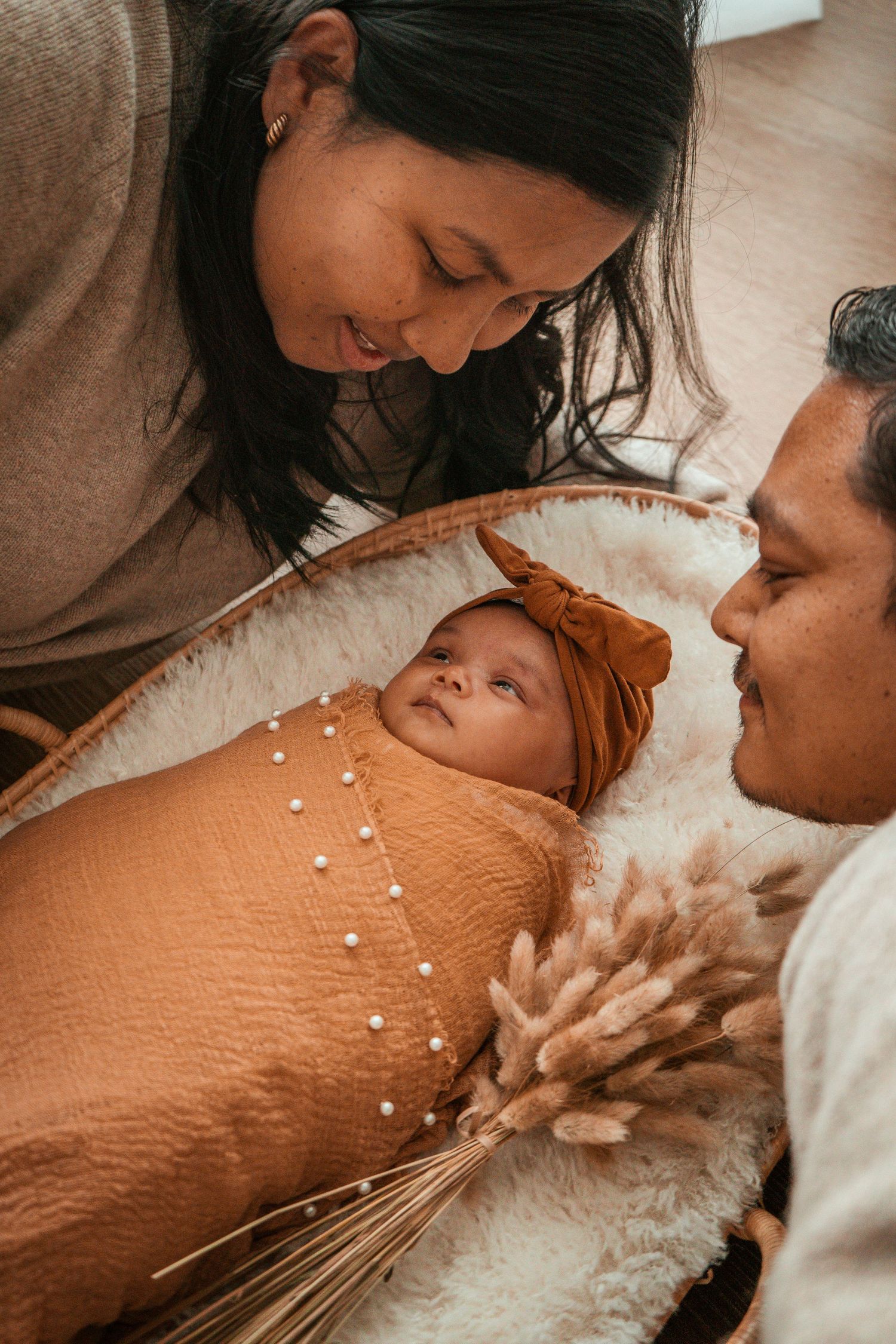 A series of intimate moments captured in warm tones showing a couple with their sleeping baby on a cozy blanket.