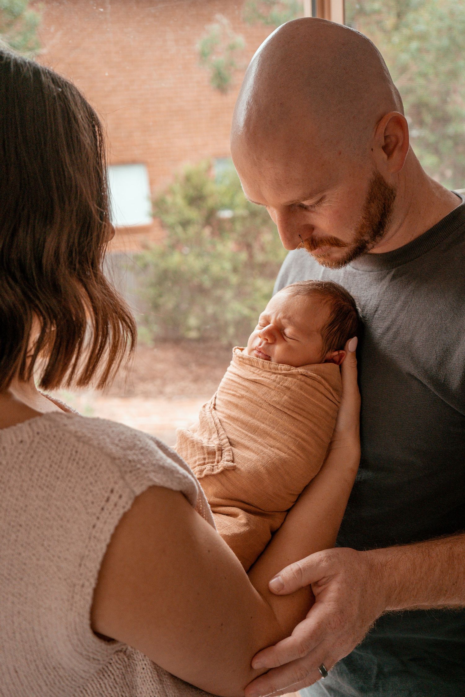A series of intimate maternity photos showing a couple embracing in warm, natural lighting with a peach-colored backdrop.