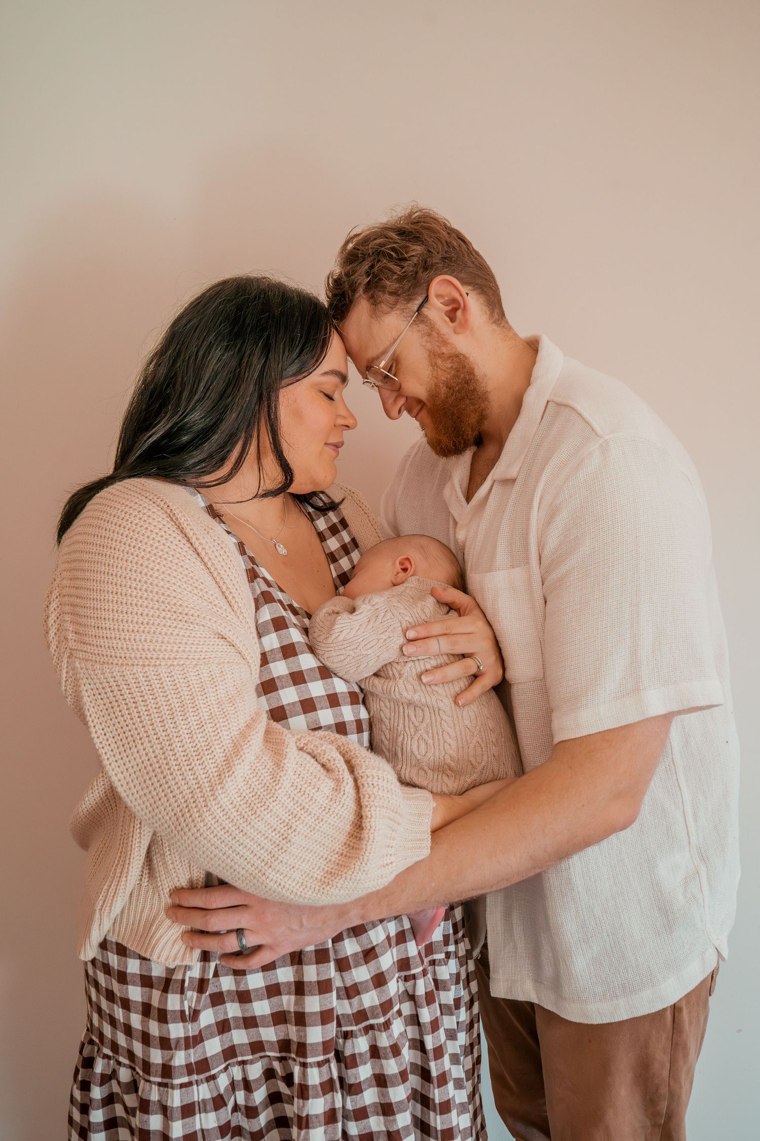 A collection of heartwarming family portraits showing parents bonding with their newborn baby in soft lighting.
