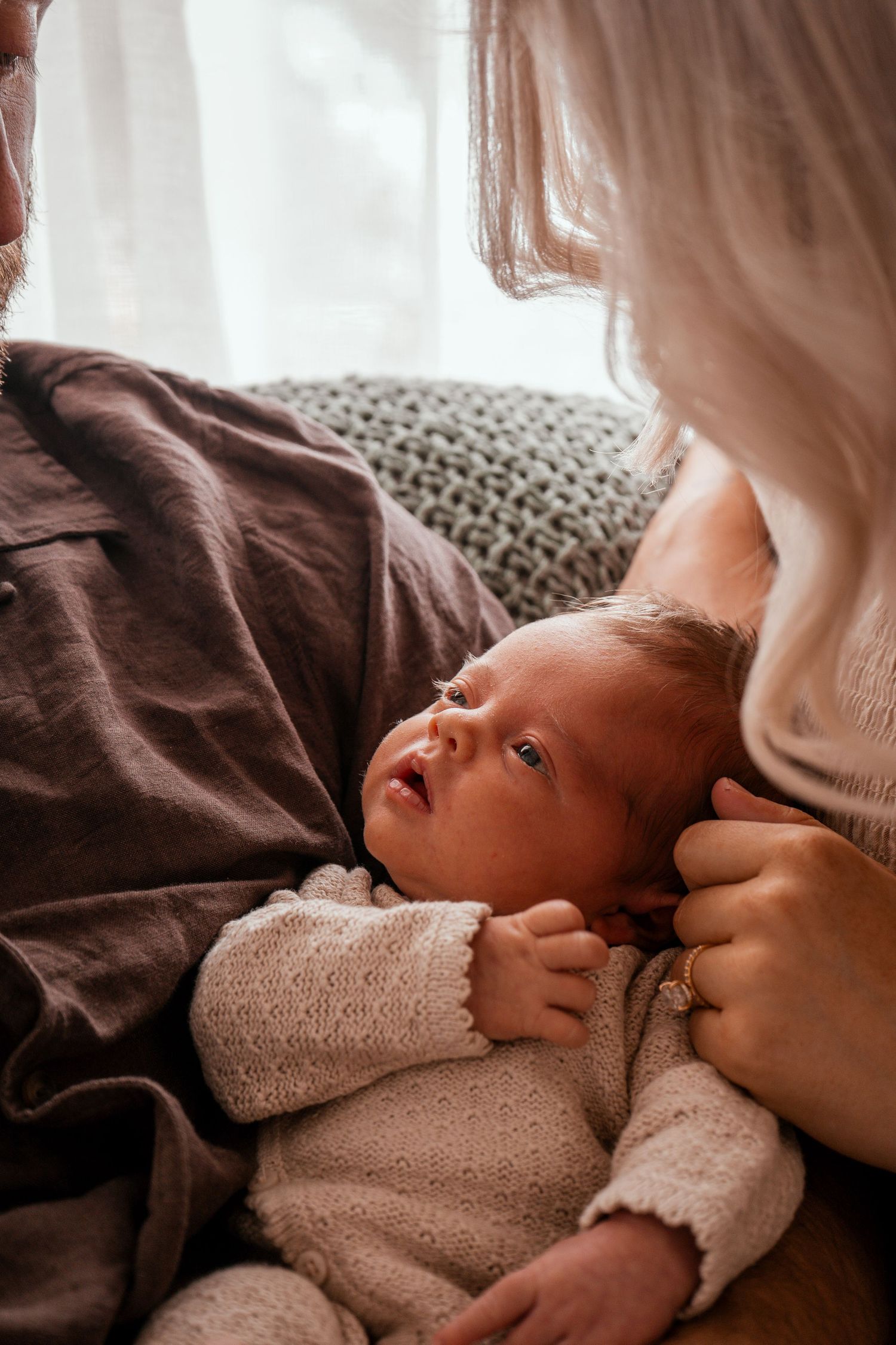 A peaceful moment captured as a sleeping newborn rests against soft fabrics in warm natural lighting.