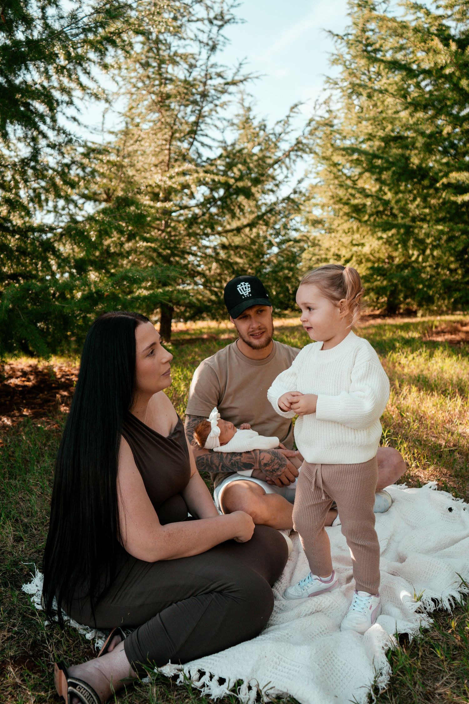 A casual family photo session outdoors with everyone dressed in coordinating neutral colors.