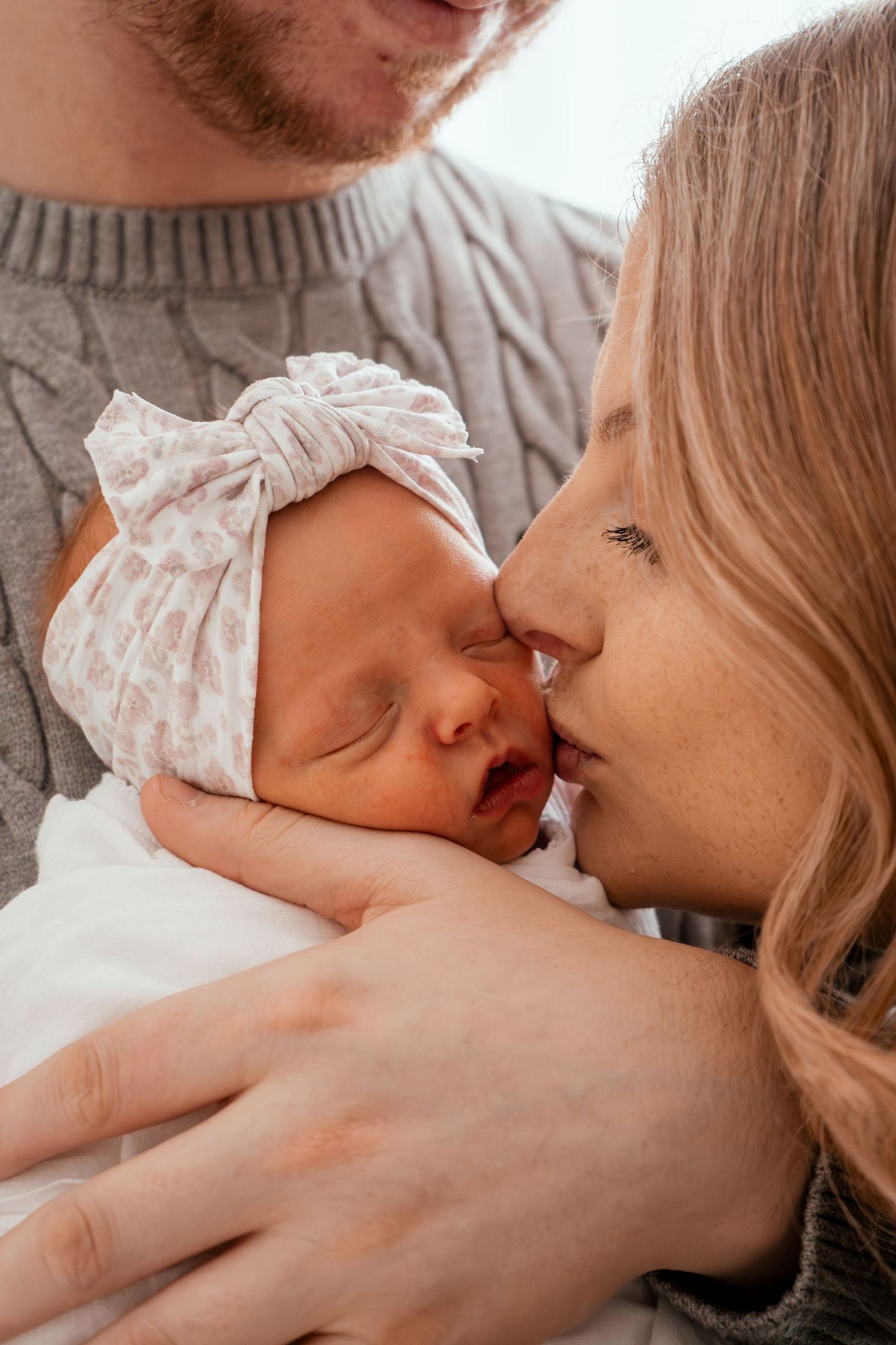 A tender moment captured in a series of intimate photographs showing a parent bonding with their newborn baby.