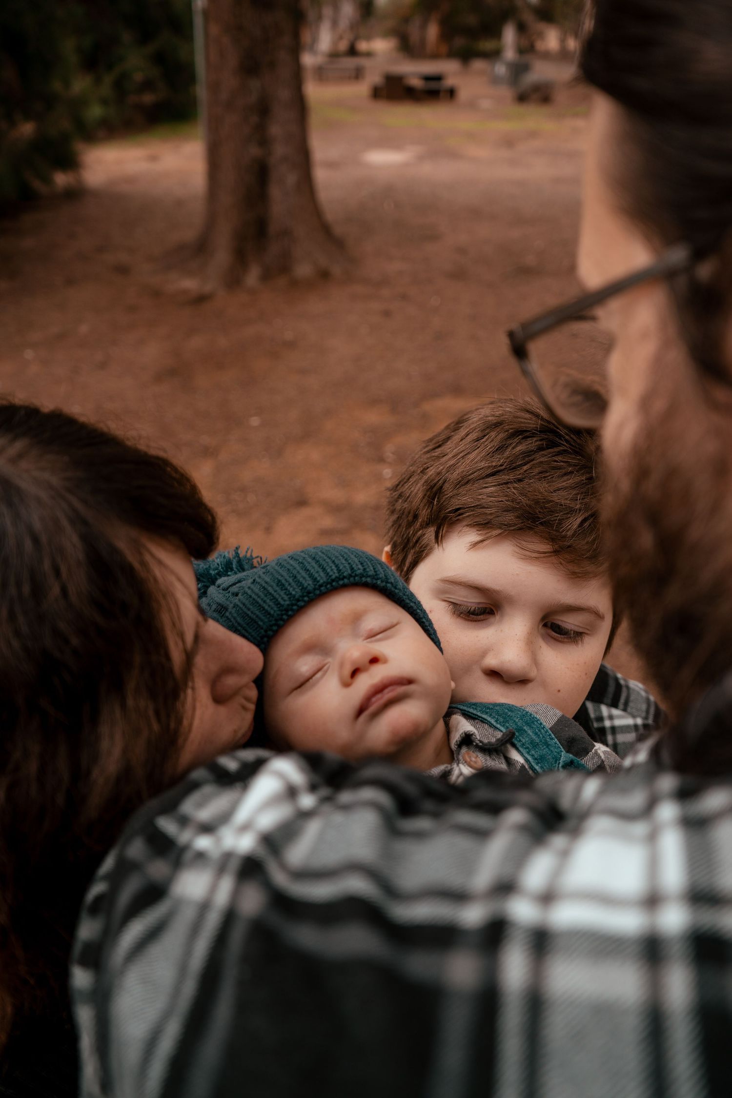A group of children rest their heads together in a close huddle formation outdoors.
