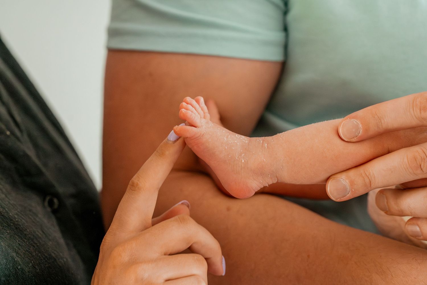 Close up view of tiny newborn baby feet being gently held by adult hands.