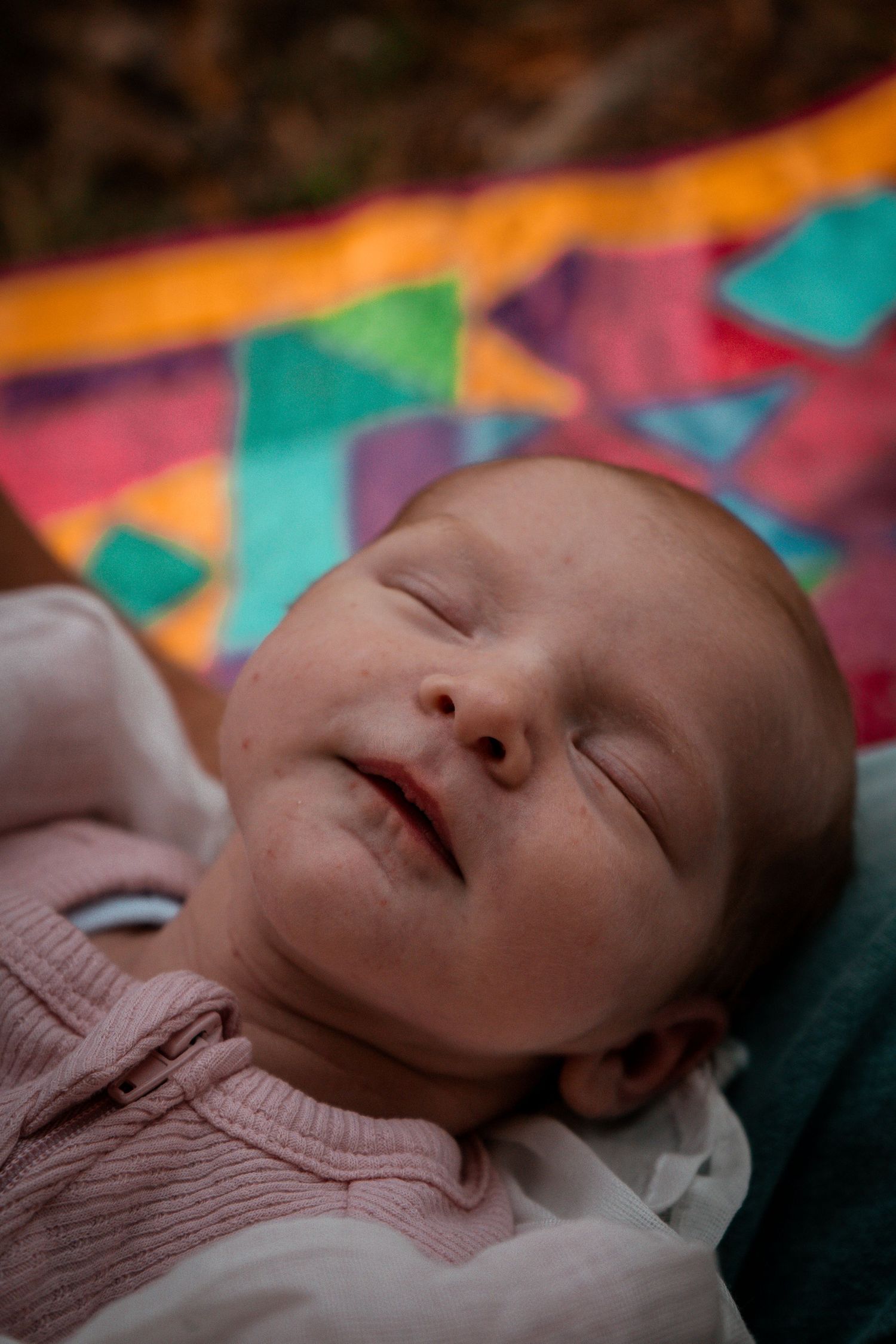 Closeup of peaceful sleeping baby against vibrant patchwork quilt background.