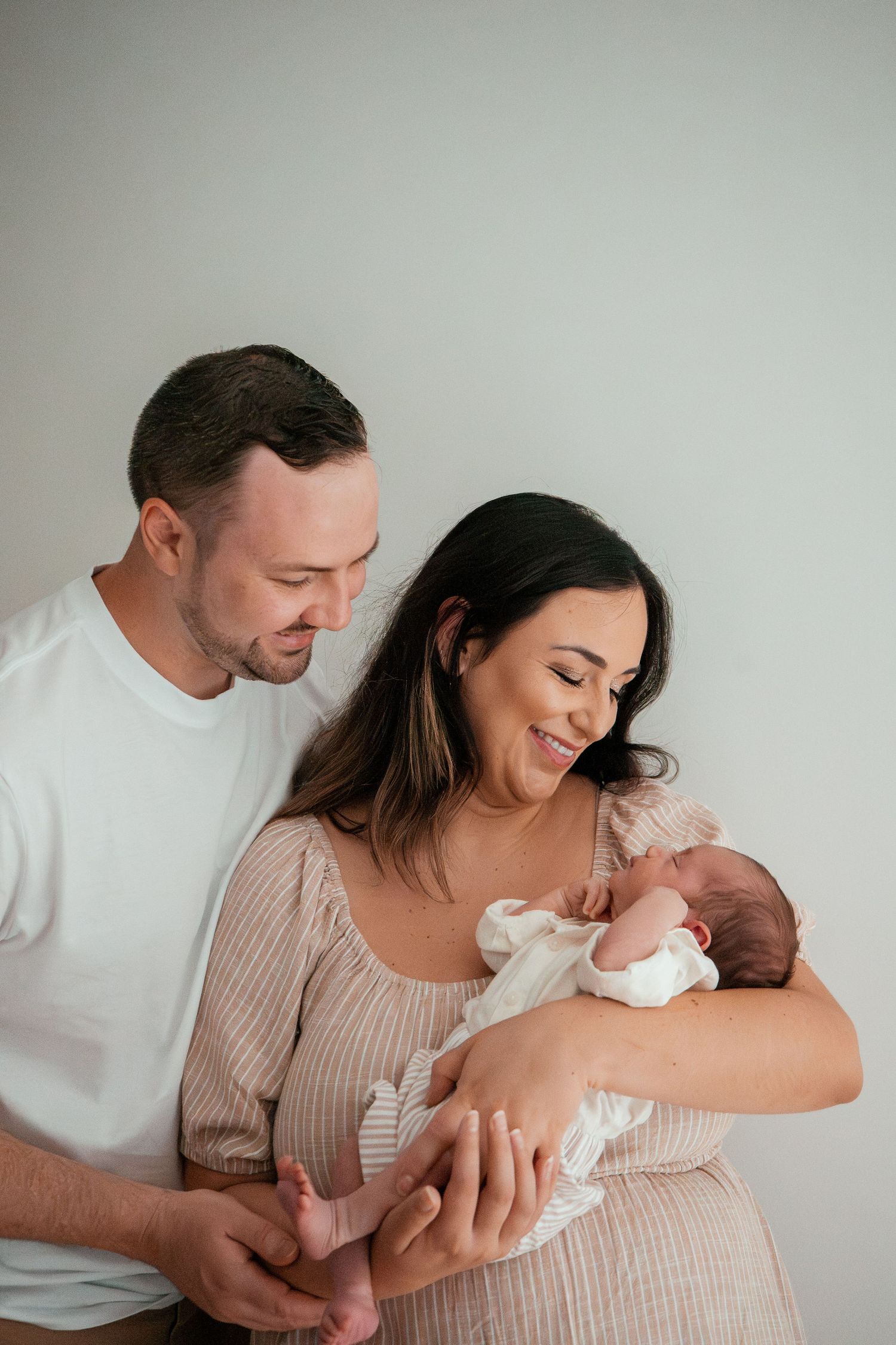 A tender moment captured in a series of photos showing parents bonding with their newborn baby in soft natural light.