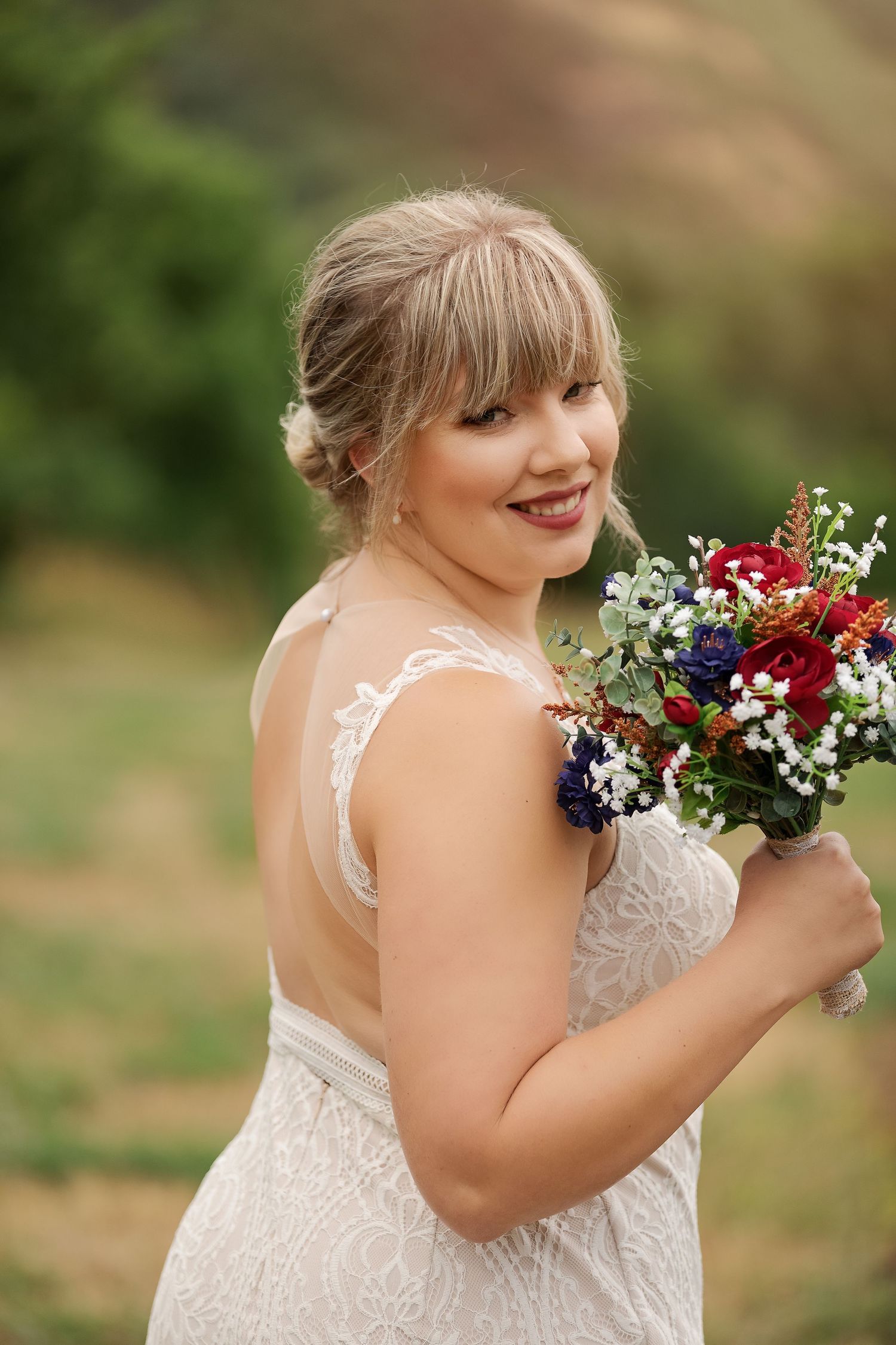 Joyful bridal portrait with colorful wildflower bouquet featuring red and white blooms.