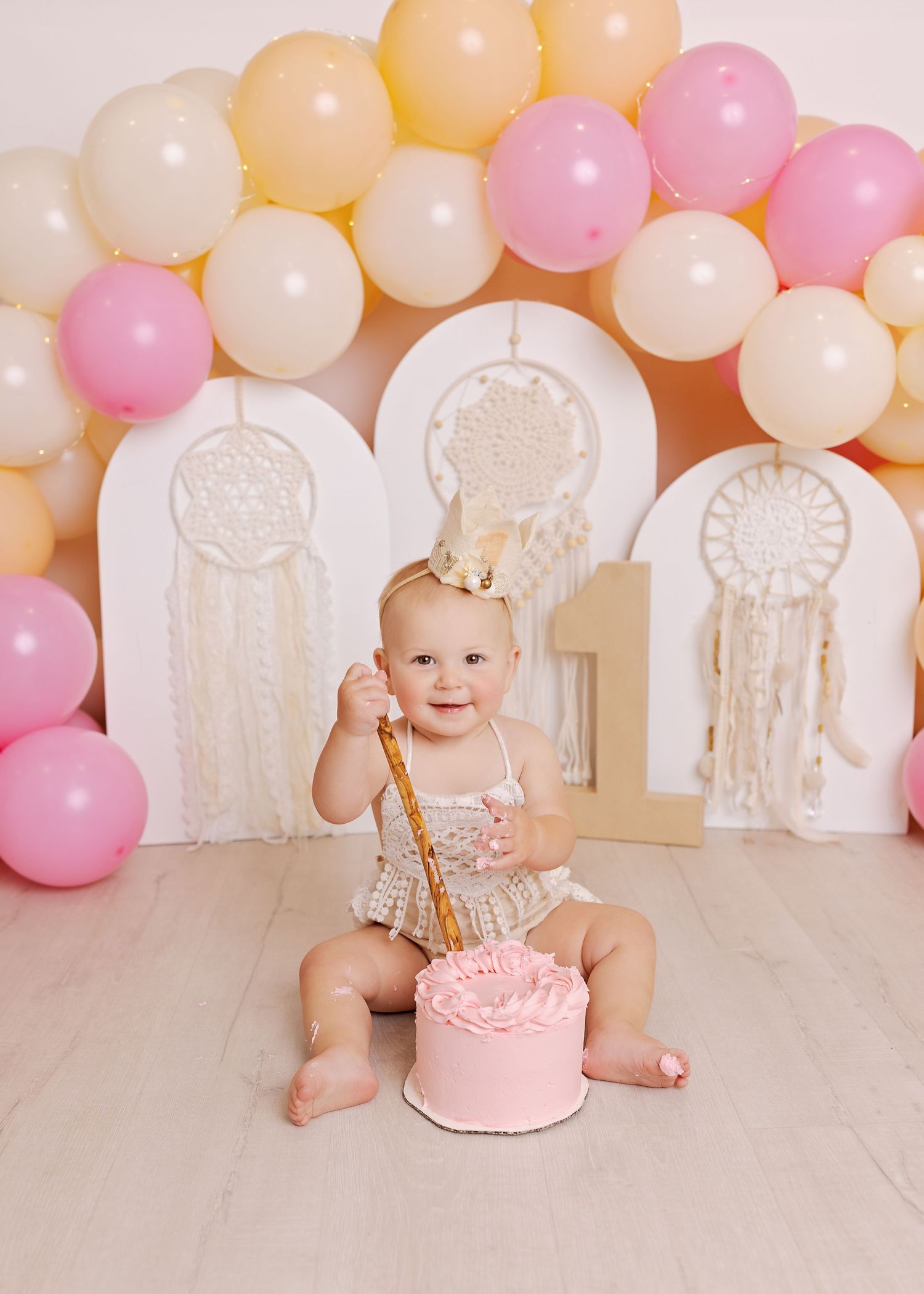 Pink and white balloons create a festive backdrop for a baby's first birthday cake smash celebration.