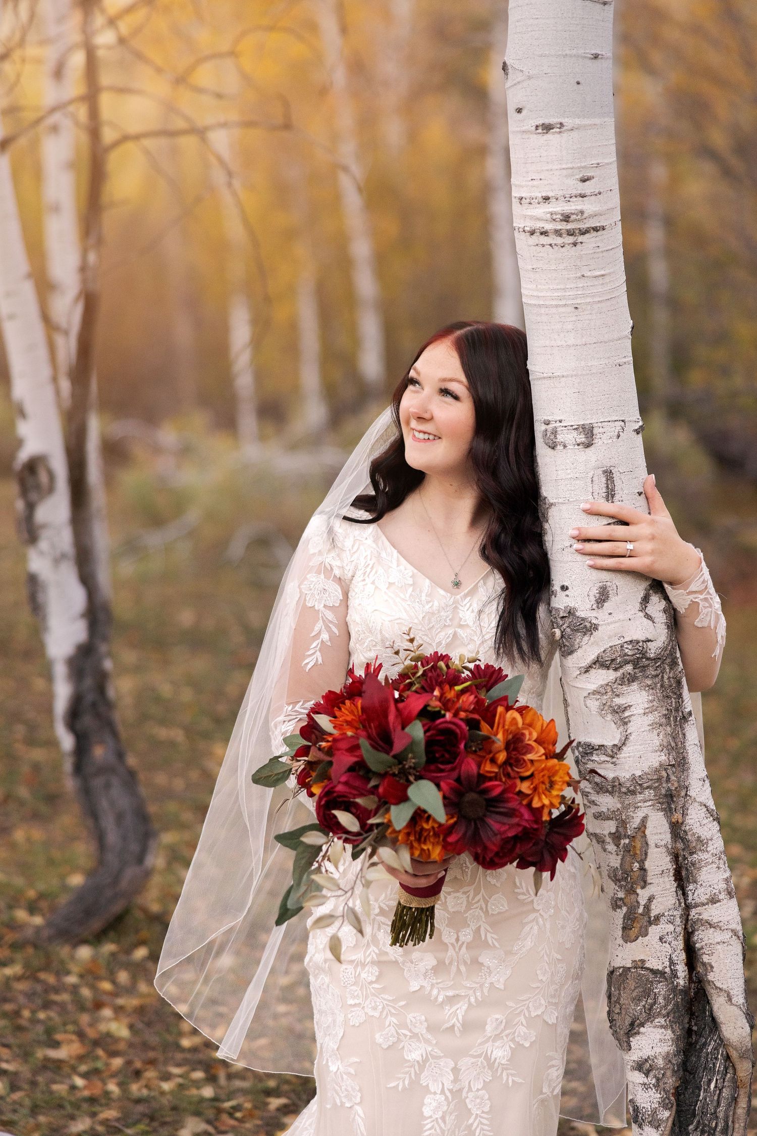 Beautiful autumn bridal photo with white birch trees and rich burgundy floral bouquet.