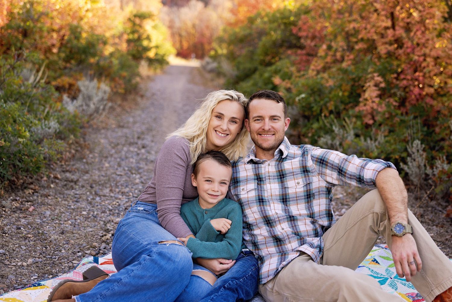 Outdoor family portrait on trail with autumn colors in background.