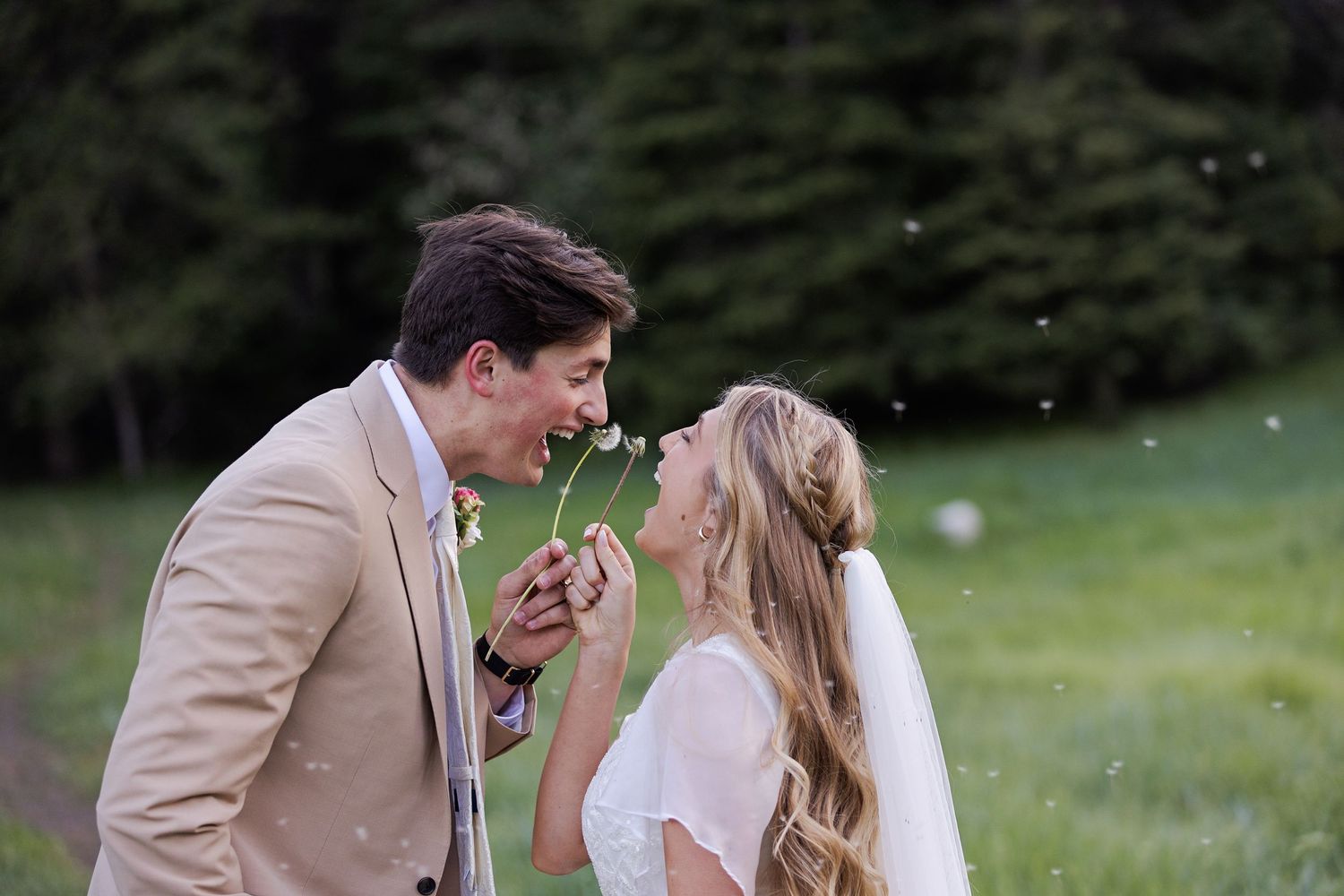A couple shares a joyful moment outdoors with flower petals falling around them.