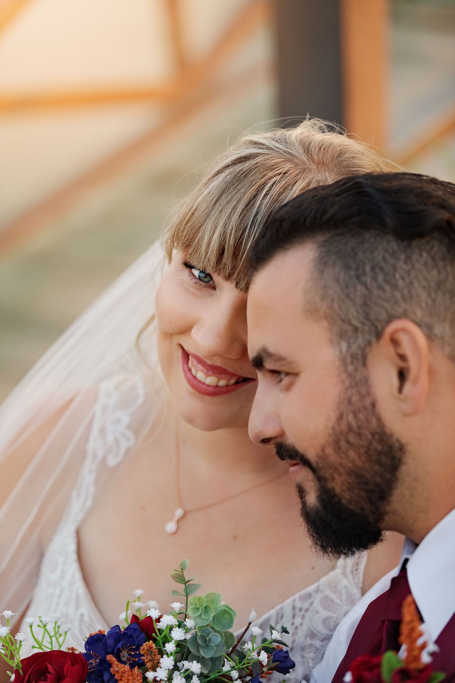 Intimate wedding portrait showcasing burgundy florals and tender moment.