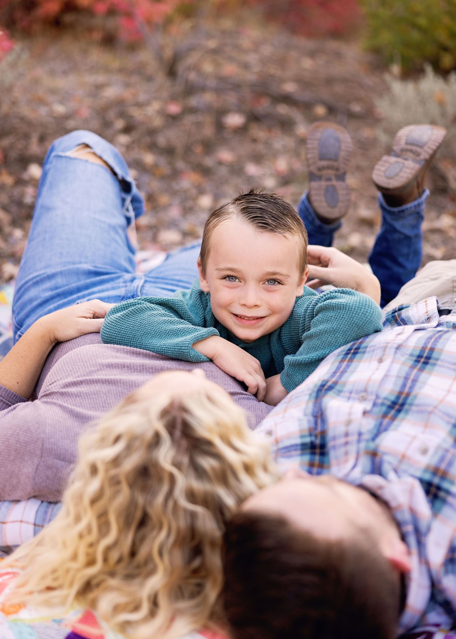 Candid moment of family lying on blanket during outdoor photo session.