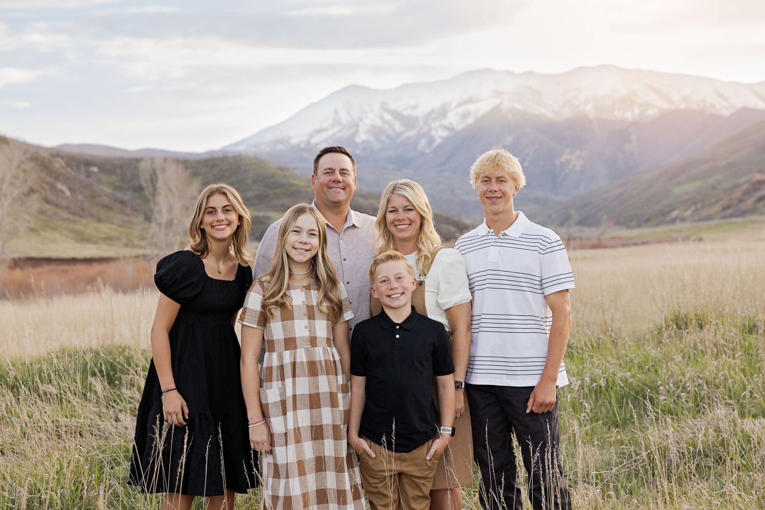 Family group photo with mountain landscape and snow-capped peaks in background.