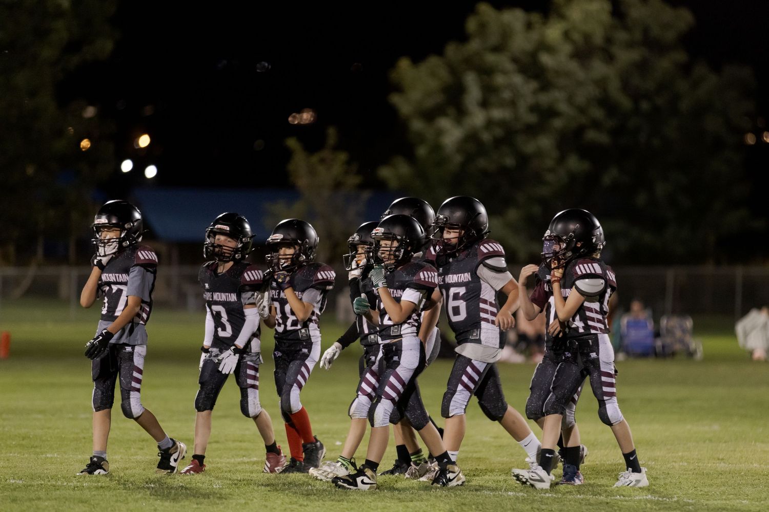 Football players line up in formation during a nighttime game on an illuminated field.