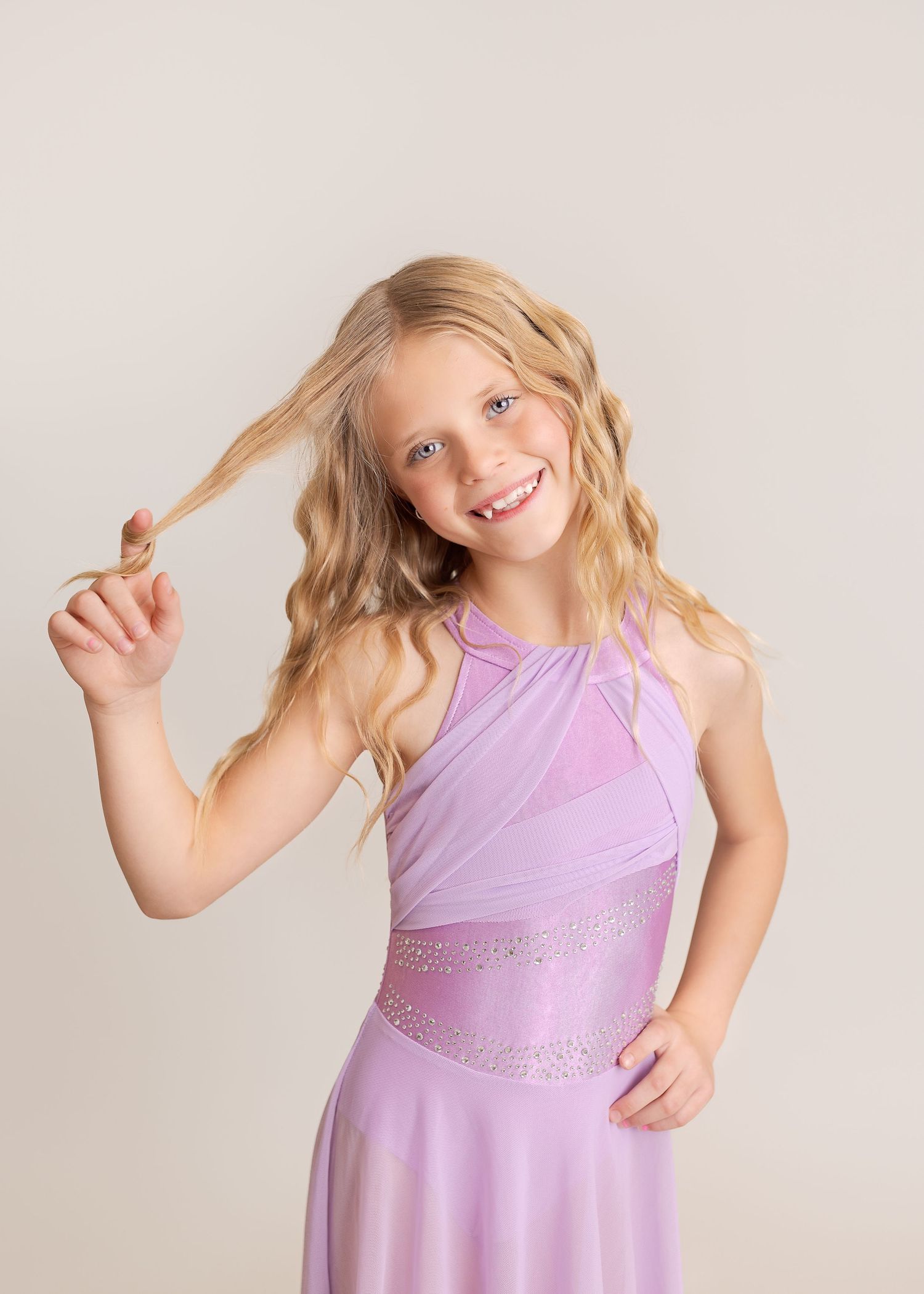 Young dancer in purple leotard poses expressively during dance performance.