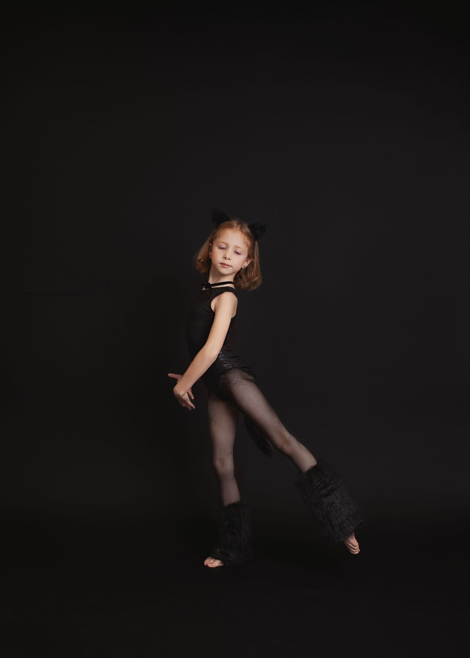 A dancer performs expressive movements in a black outfit against a dark background during a dance sequence.