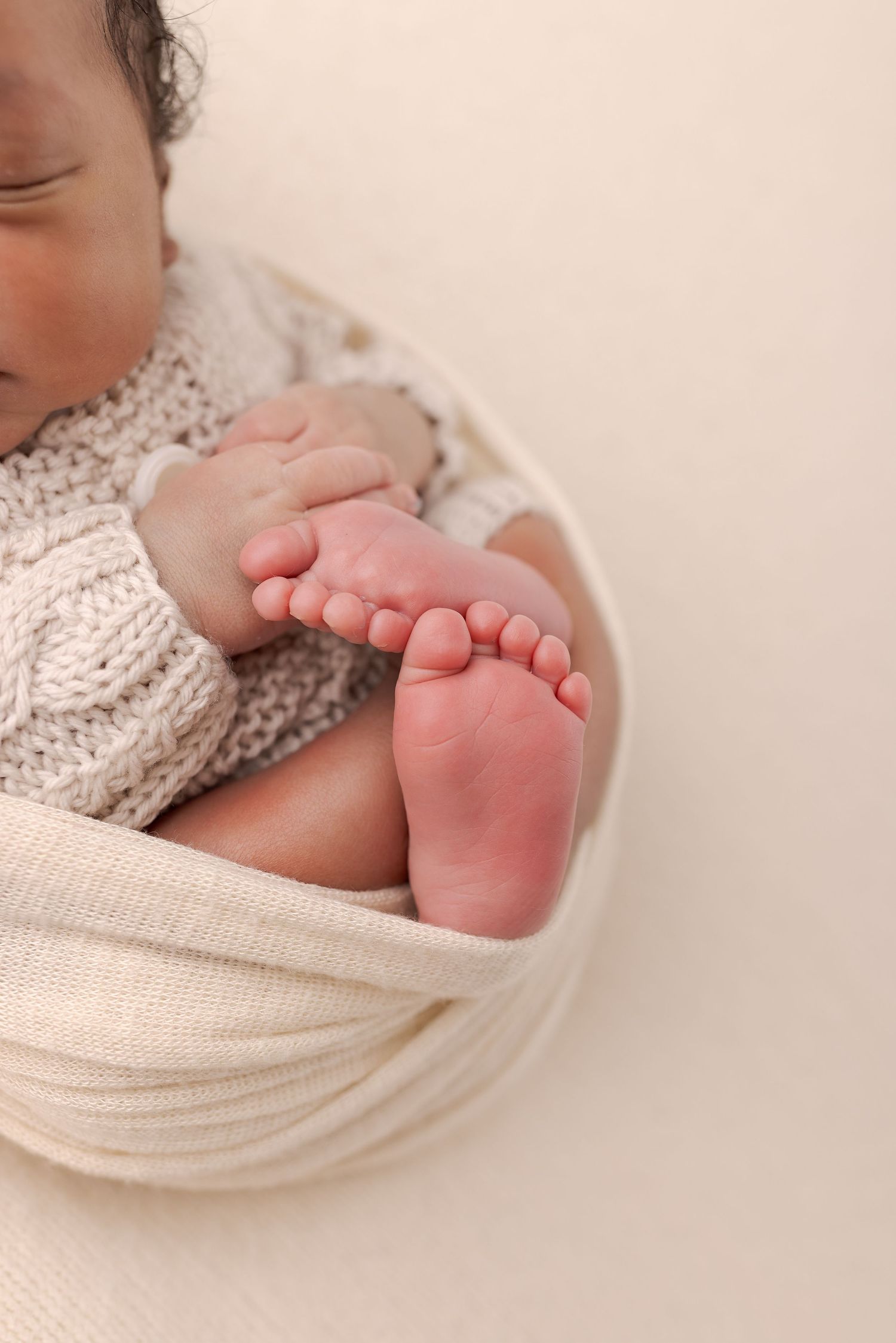 Close-up series of tiny baby feet in soft knit blankets showing delicate toes and skin texture in warm lighting.