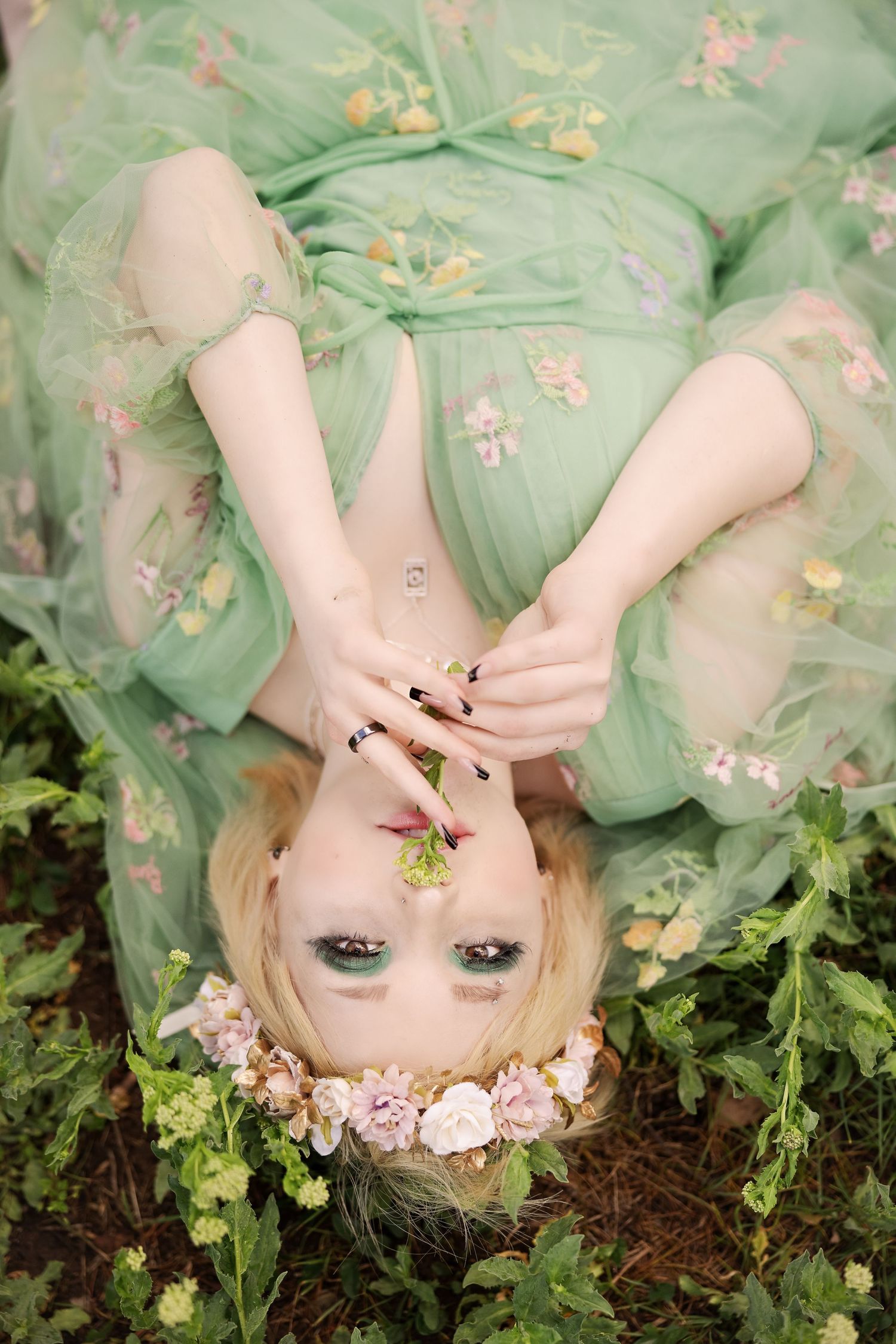 Artistic overhead shot with mint floral dress surrounded by greenery.