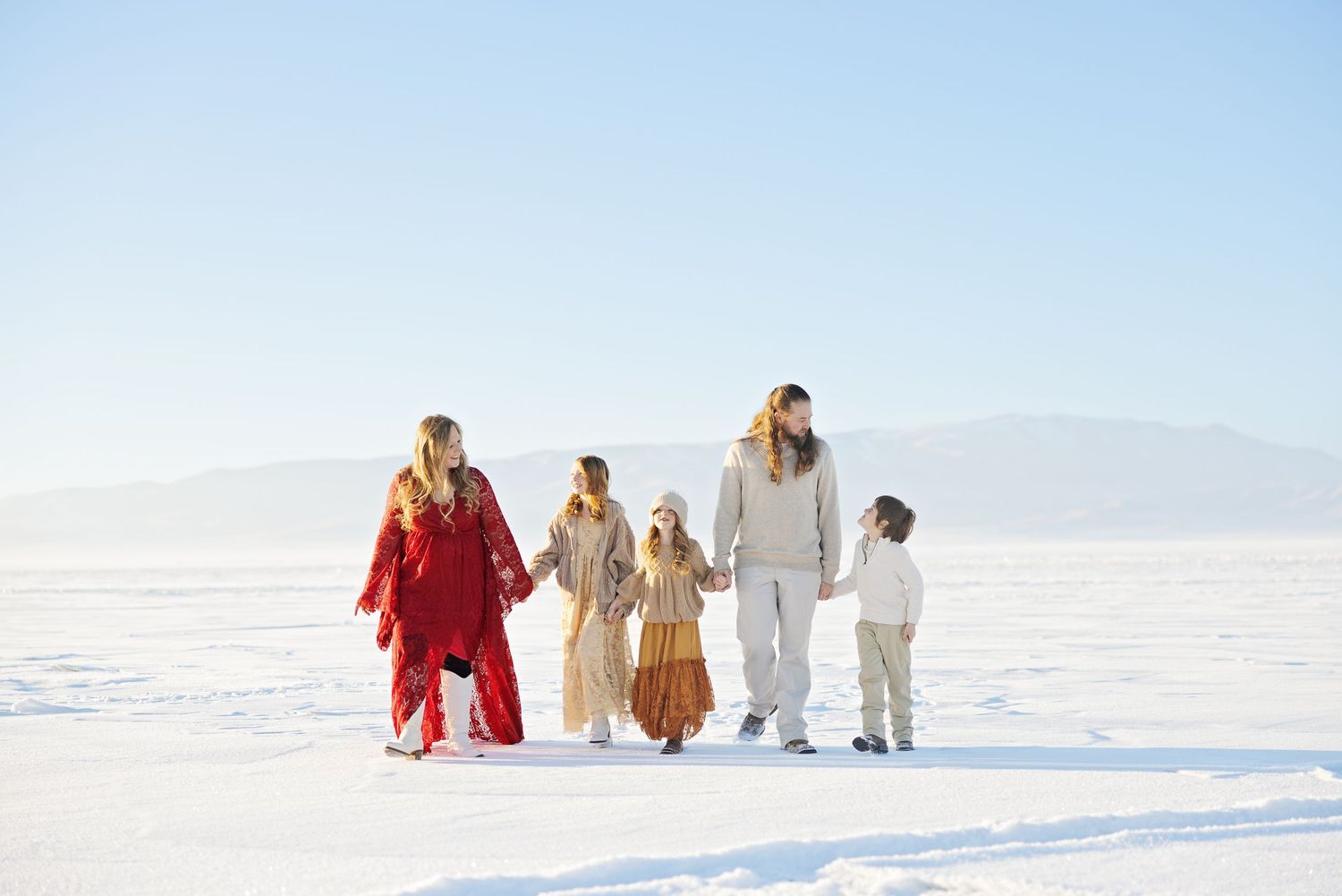 Family walking together across white salt flats wearing coordinated bright outfits.