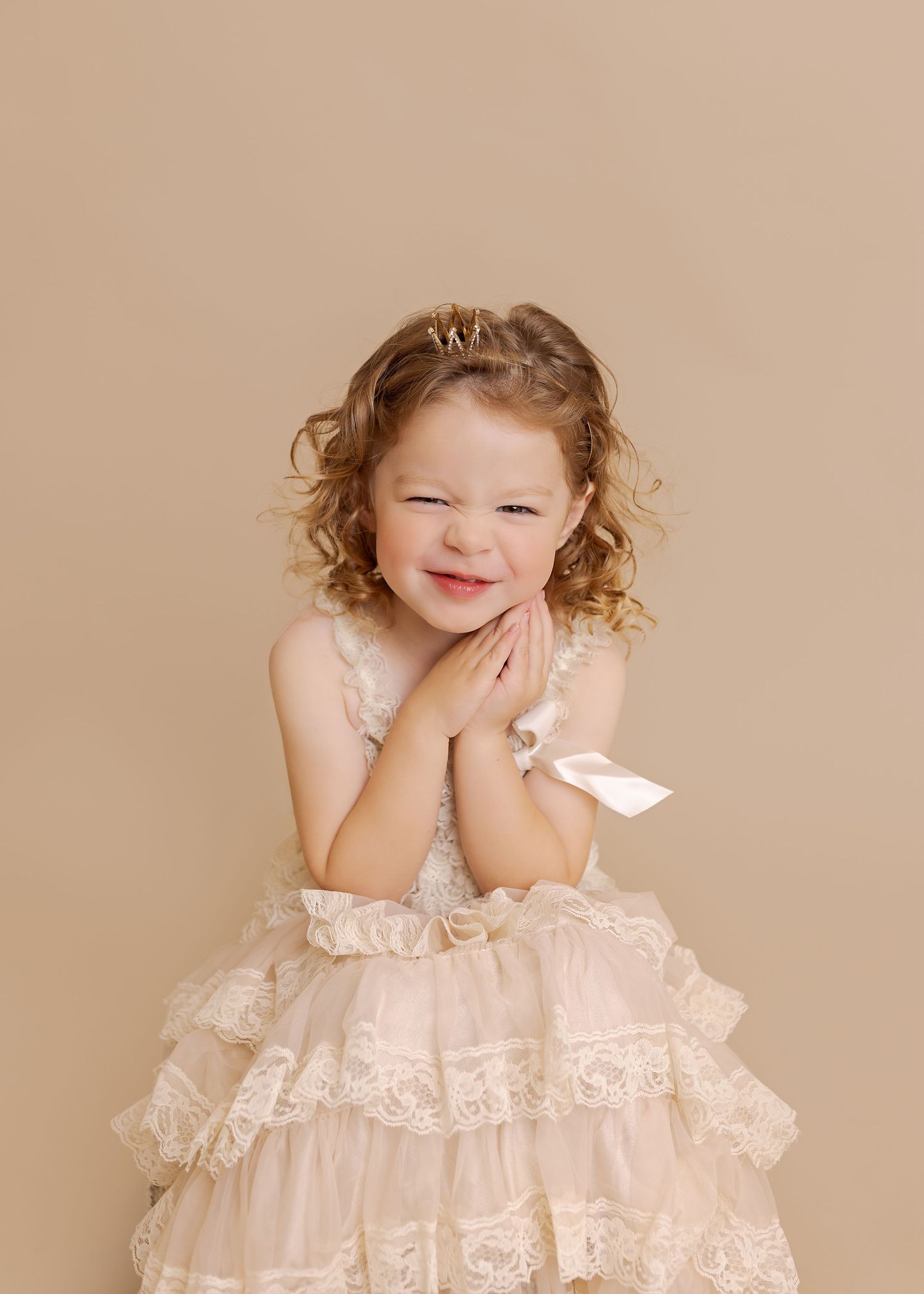 A series of four photos showing a child in a delicate cream lace dress against a neutral beige background.