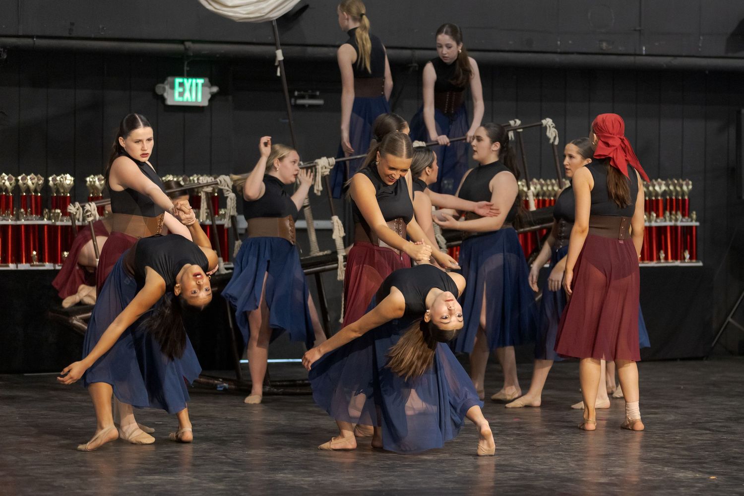 Modern dancers perform an expressive contemporary piece in flowing blue and red costumes on a dark stage.