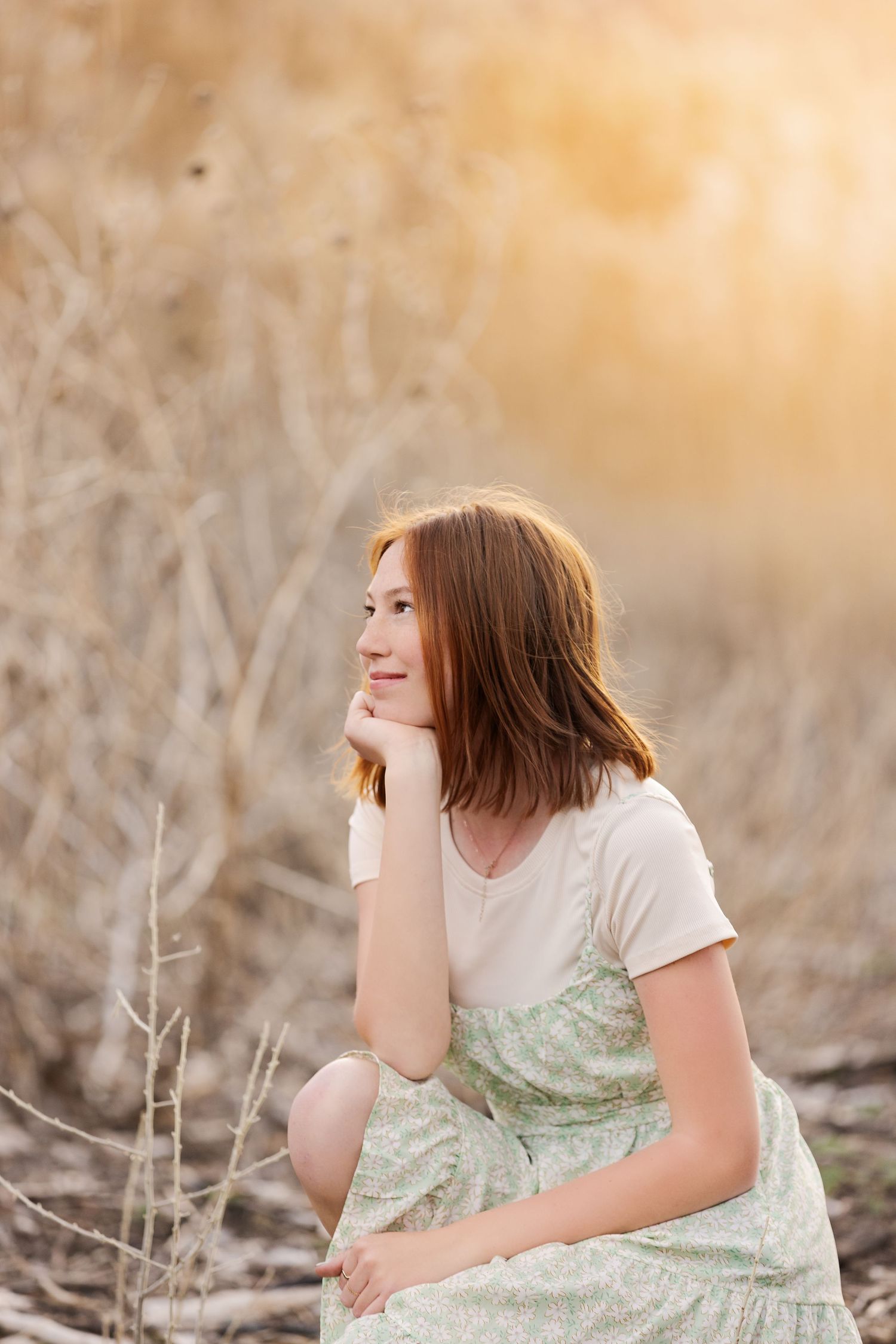 Thoughtful pose in a mint dress among dried grasses at golden hour.