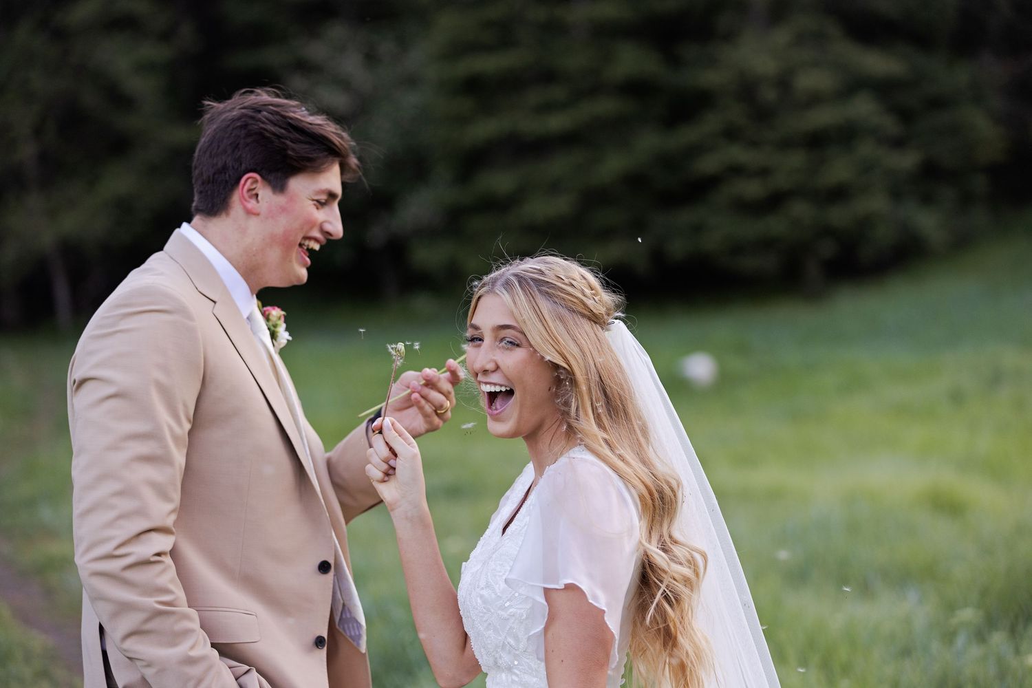 Couple shares a playful moment surrounded by nature at their outdoor wedding celebration.