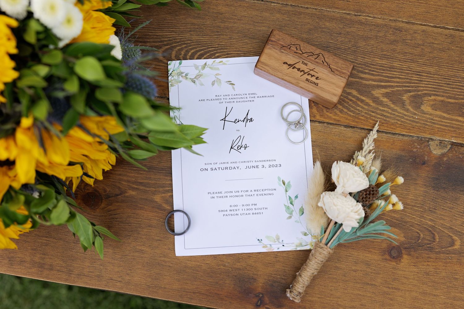 Wedding invitation on wooden surface with sunflowers and boutonniere decoration.