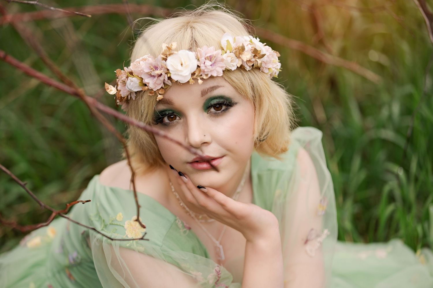 Ethereal portrait in mint green dress and pink flower crown against natural backdrop.