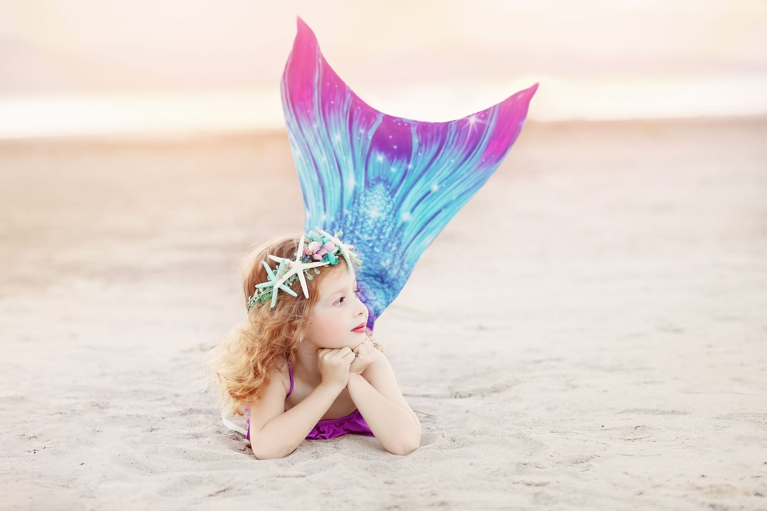 A magical mermaid photoshoot on the beach with vibrant blue and purple tail.